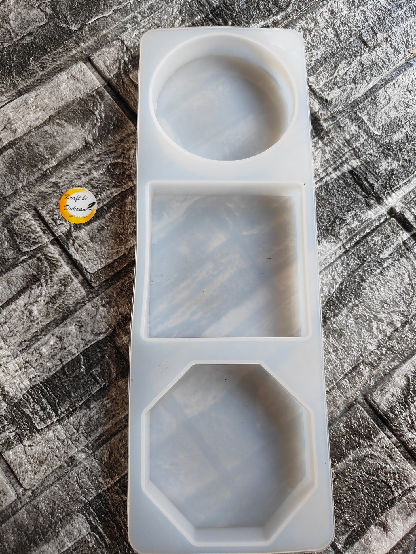 White silicone 3 in 1 paperweight mold with circle, square, and octagon shapes on textured surface