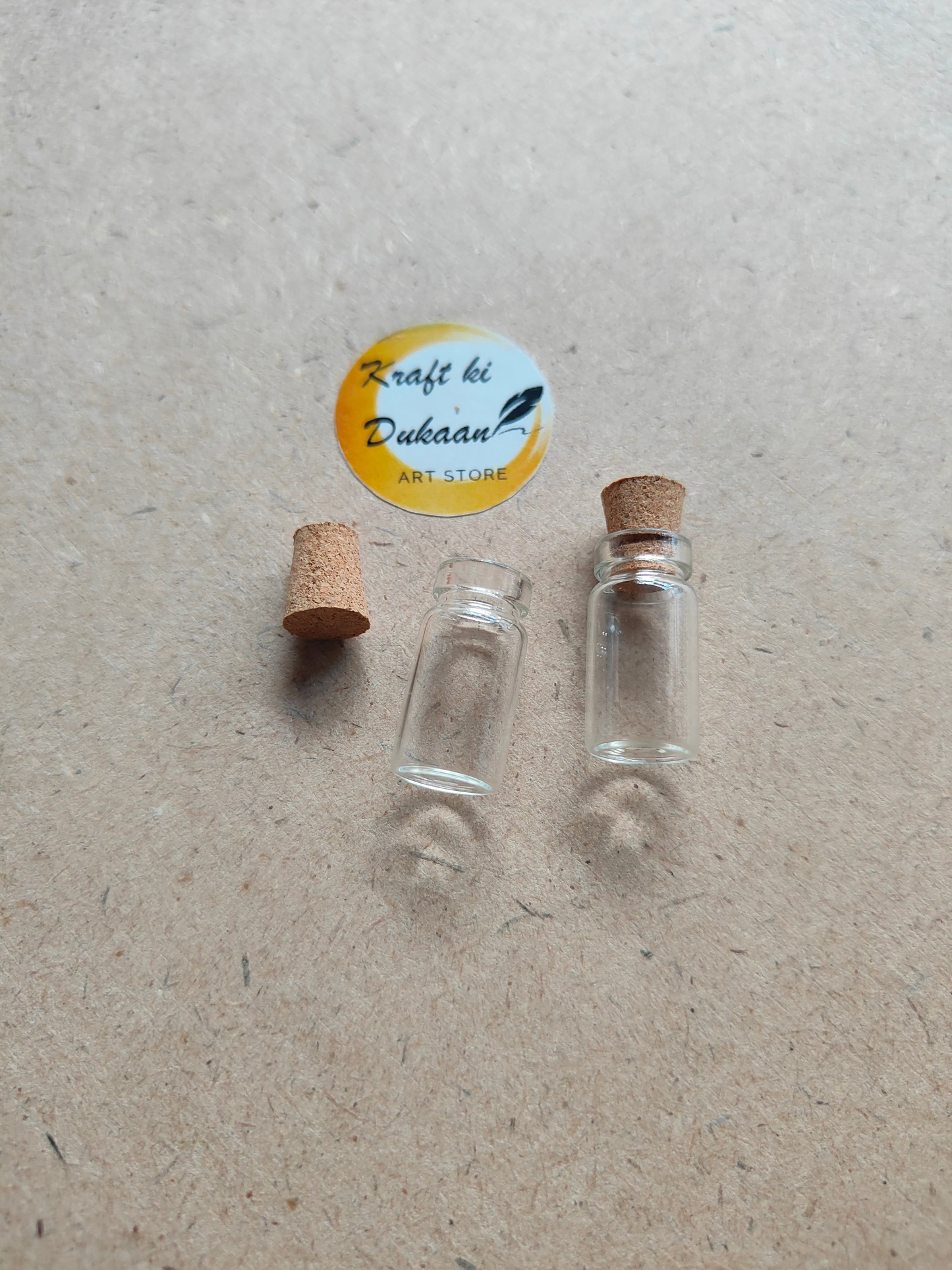Two small glass bottles with cork stoppers on a textured surface
