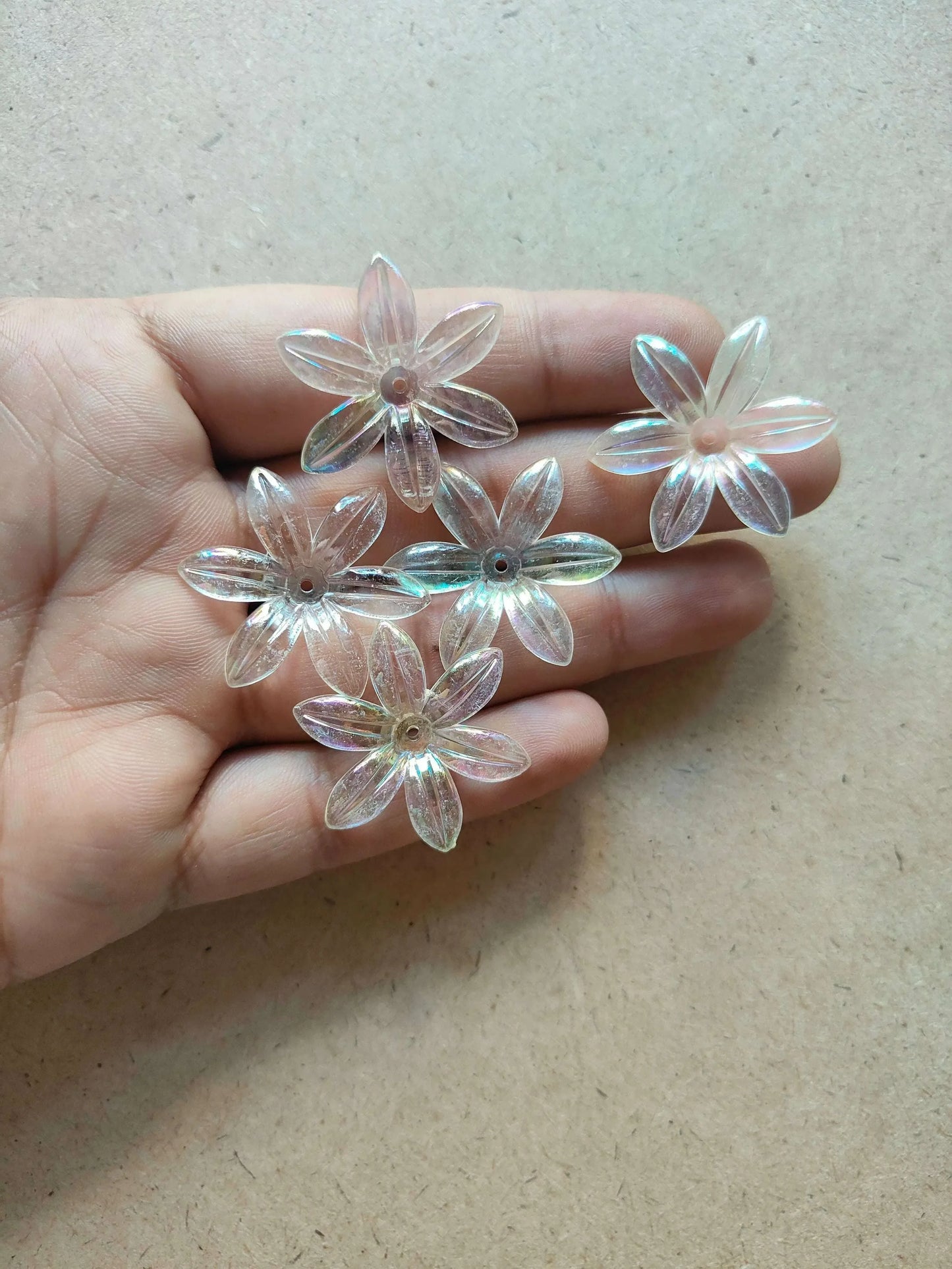 Transparent rainbow flower beads, five flower charms resting in palm