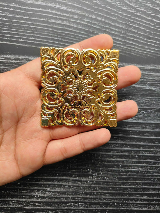 Handheld view of golden ornate square t-light plate with decorative filigree plastic