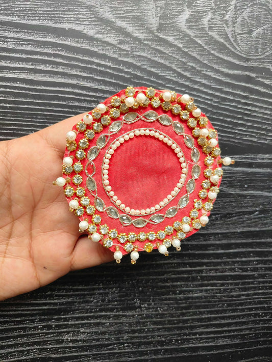 Red round decorative patch with pearl border, gold studs and bead tassels