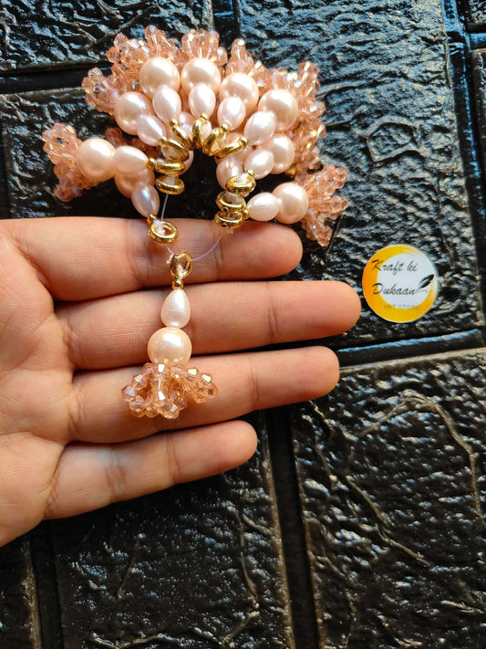 Pearl and peach bead latkan pair with gold loops and dangling tassels, held in hand