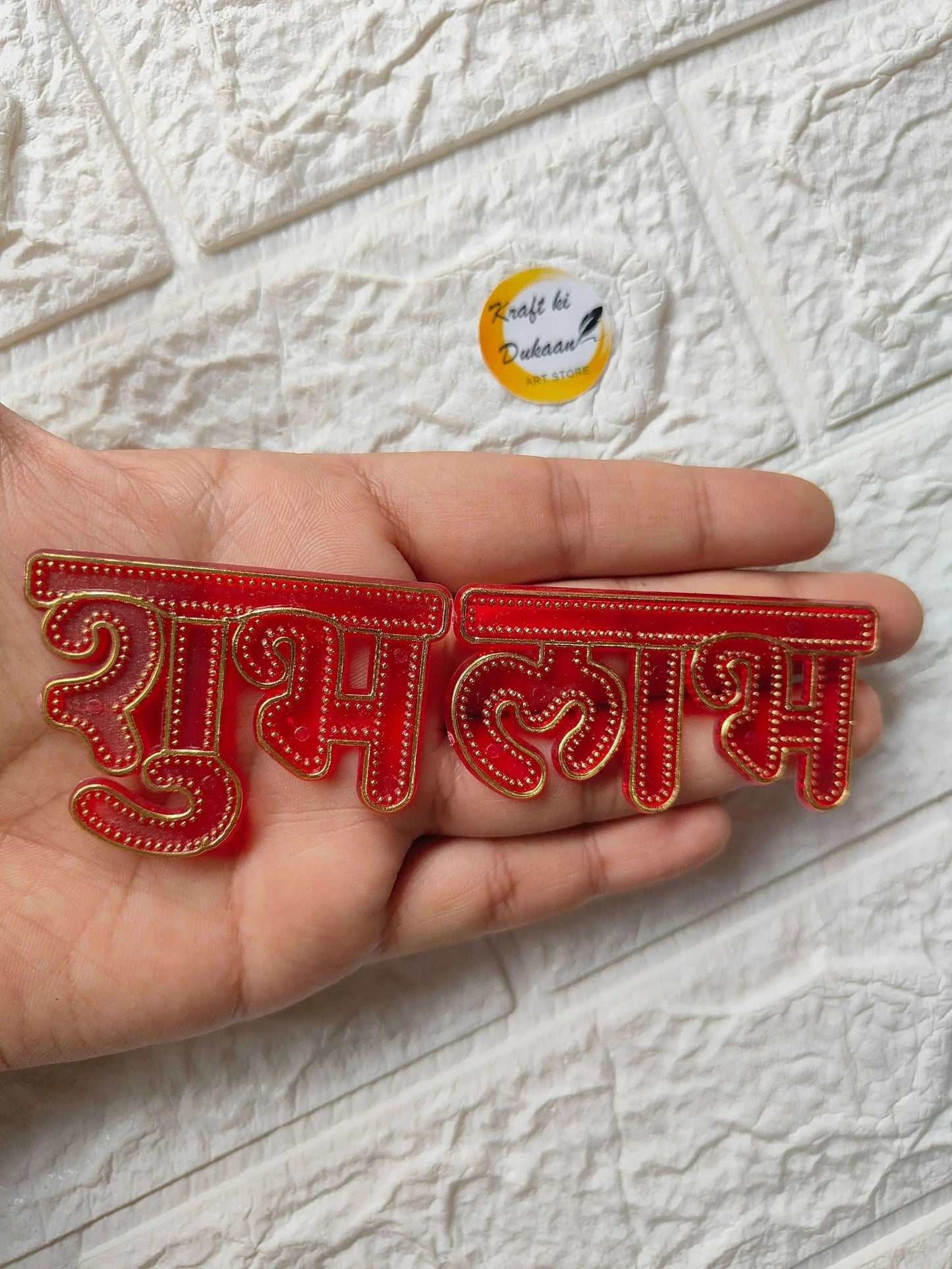 Acrylic Shubh Labh cutout strip in hand, red base with gold stitched detailing