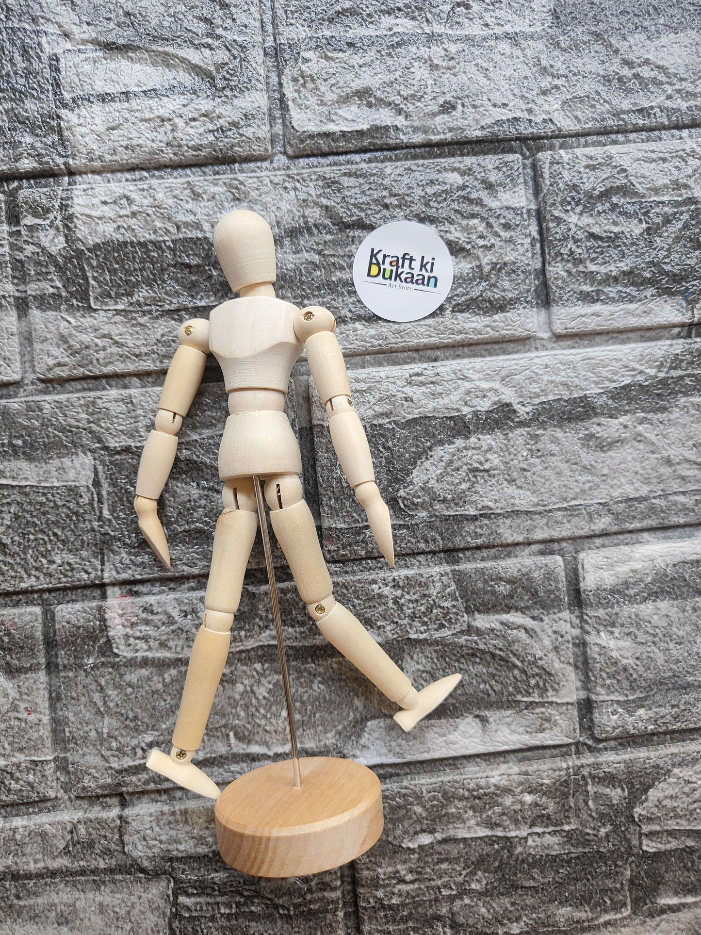 Wooden manikin with articulated arms and legs on round wooden base stand