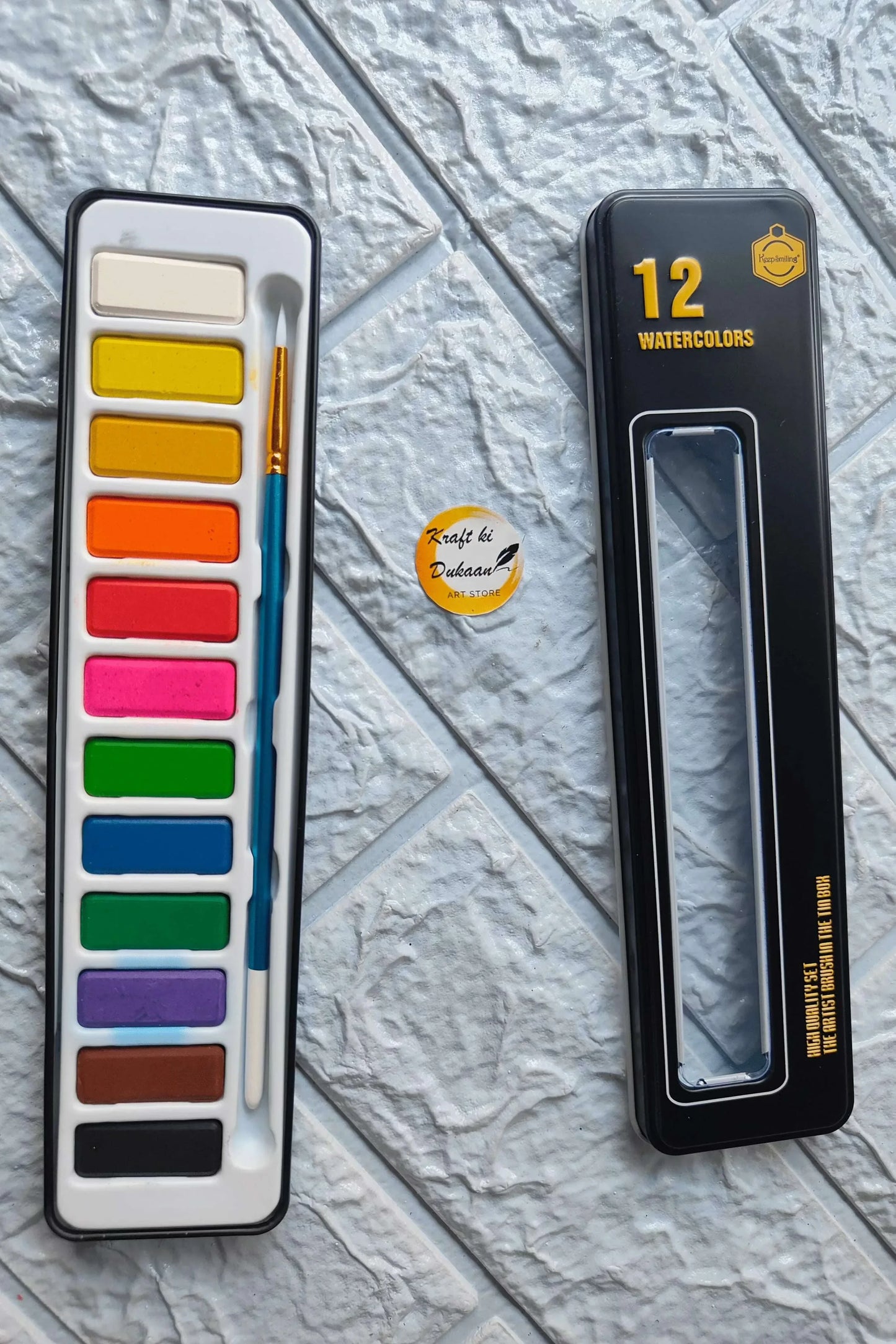 Watercolor paint box with 12 colors, open tray showing rainbow palette and brush