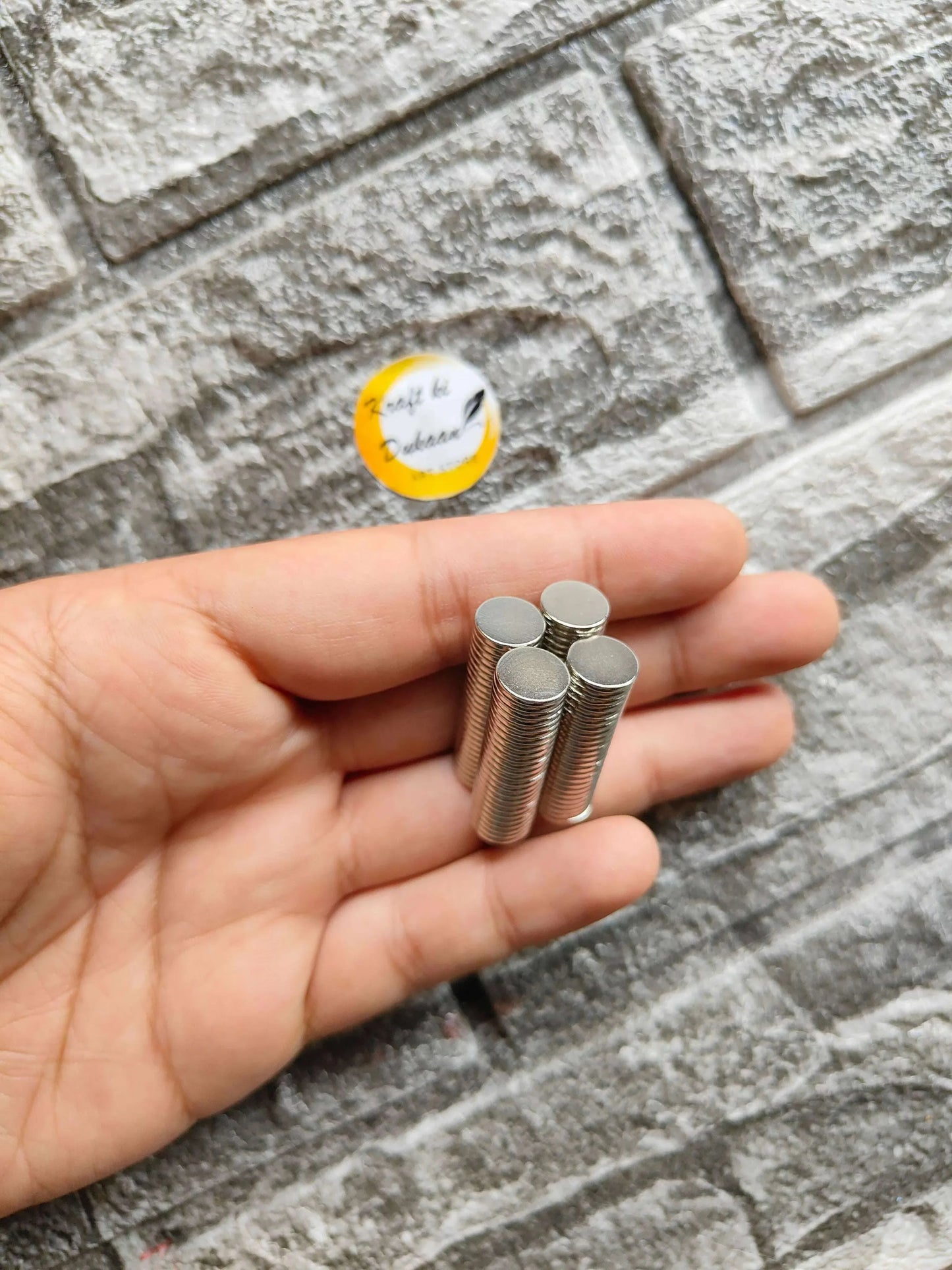 Loose 10x1.5mm round steel magnets in palm, silver ends and discs