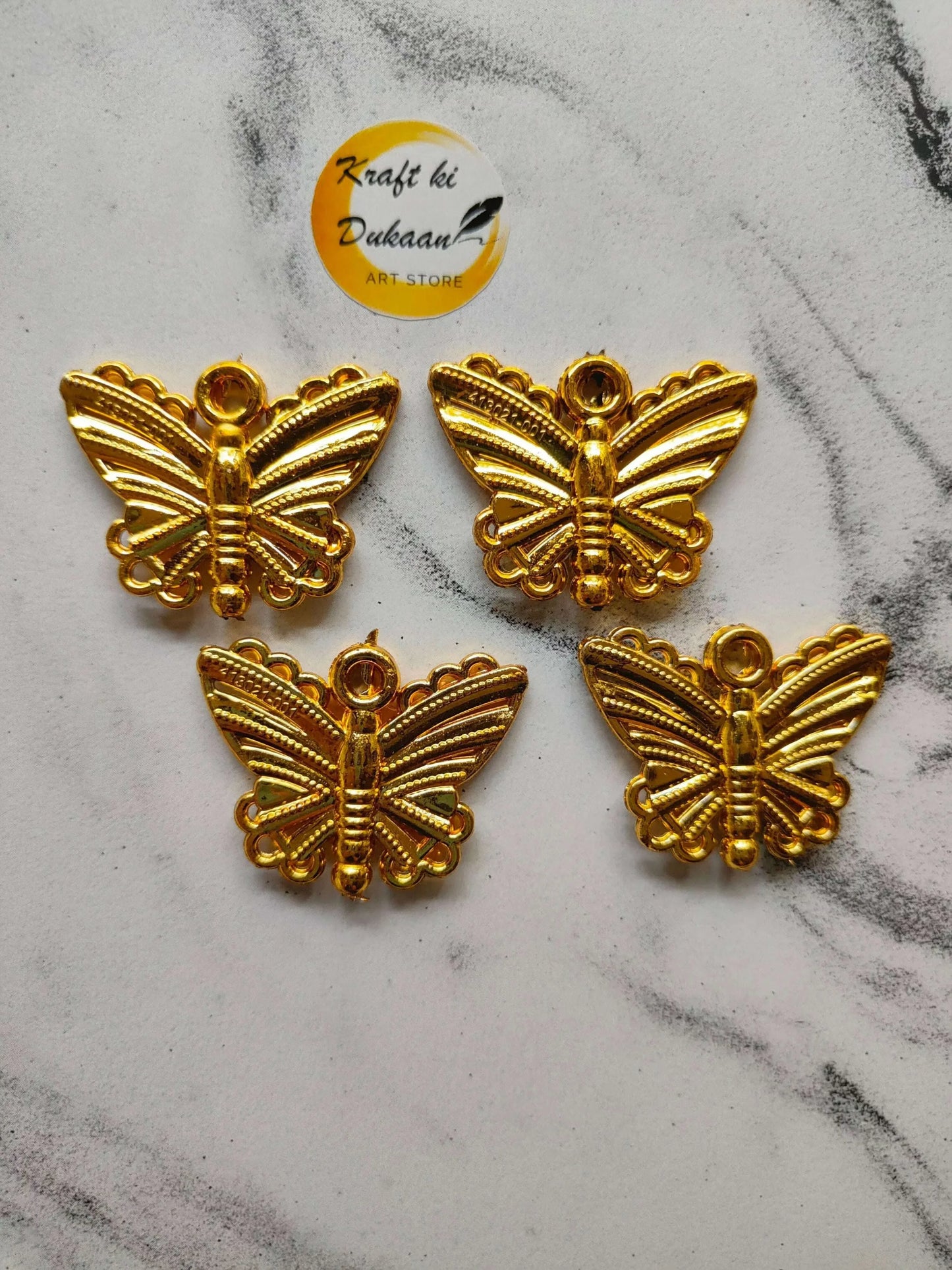 Butterfly design bead charms, gold tone, four pieces laid out