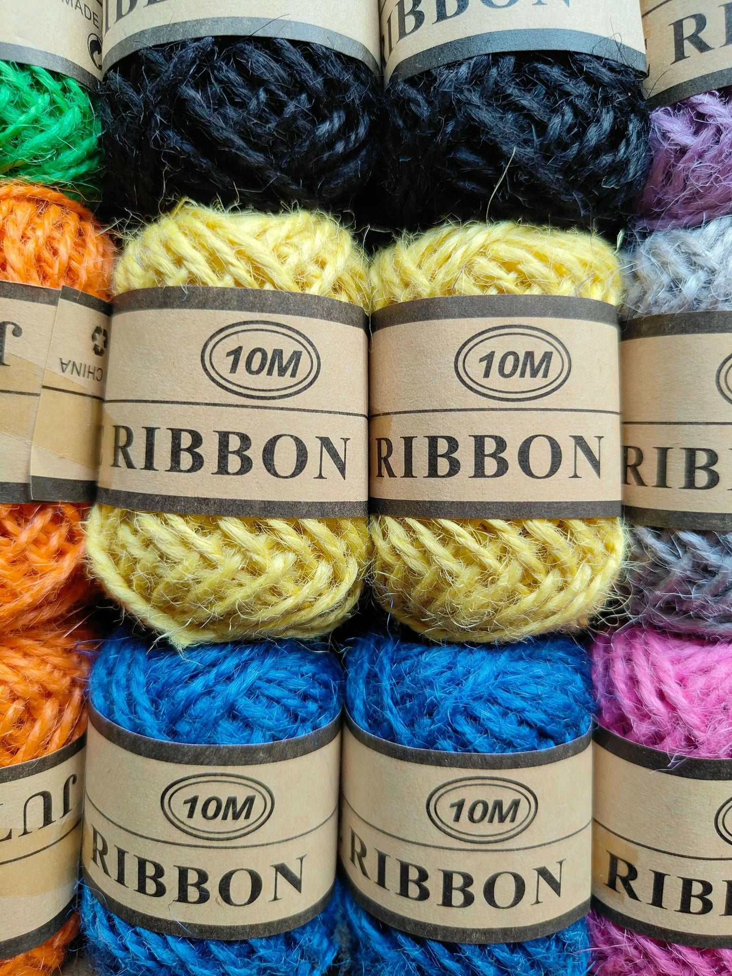 Close-up of colored jute thread skeins with “10M” labels: black, yellow, blue, pink, green