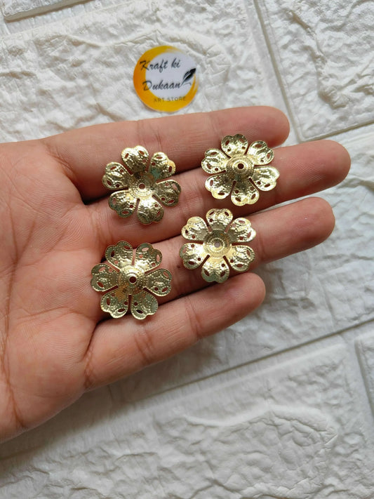 Gold metal flower buttons in hand, detailed petal edges and central hole