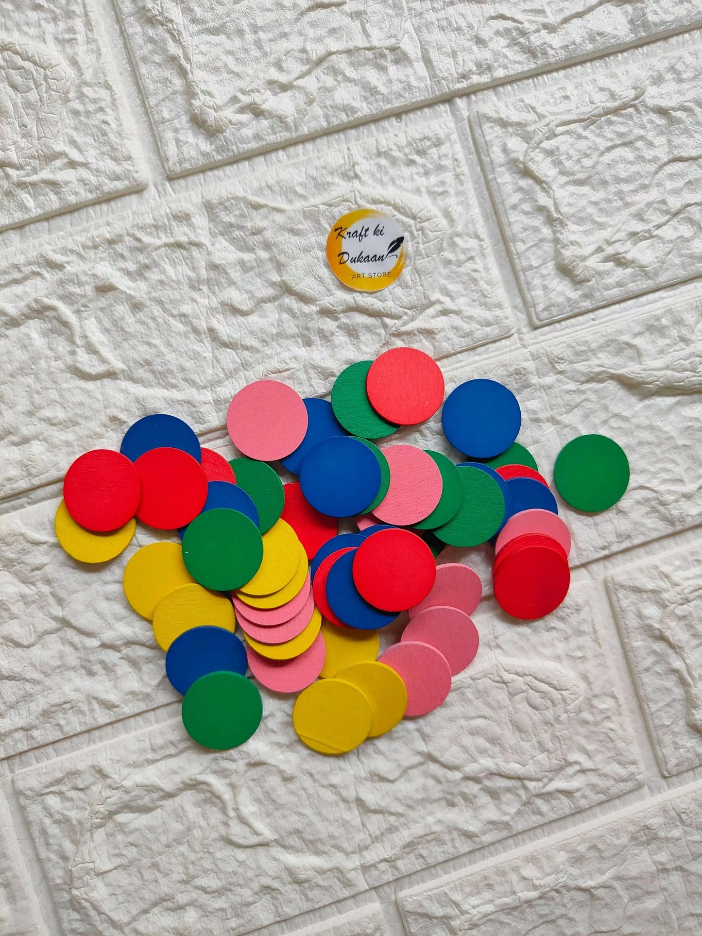 Wooden round color block pieces in red, blue, pink, green, yellow, scattered