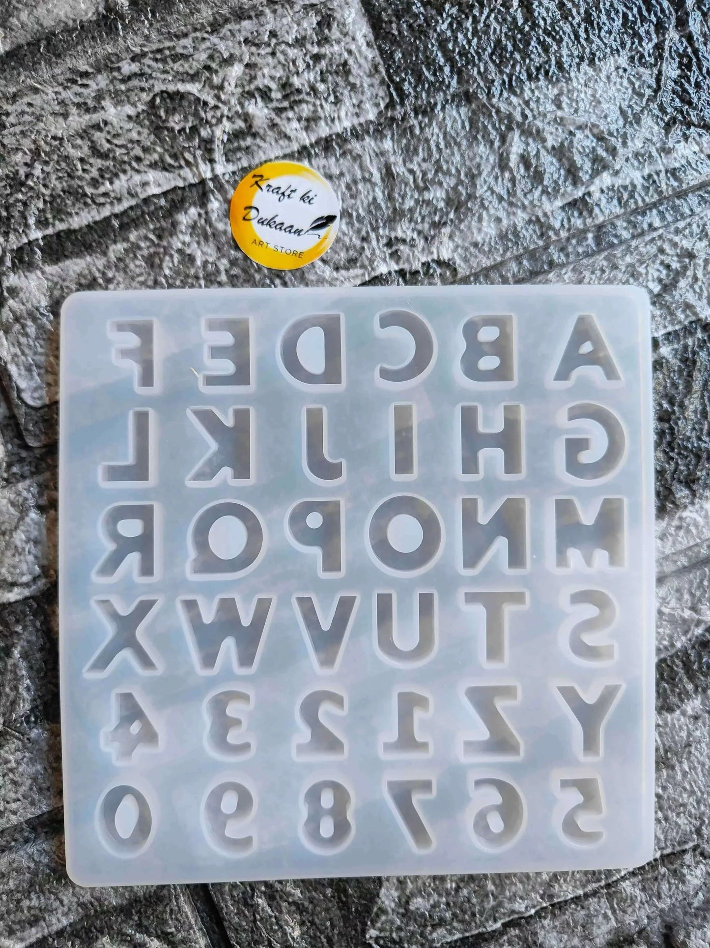 Small alphabet mould with raised letters and digits, arranged in a clear plastic grid tray