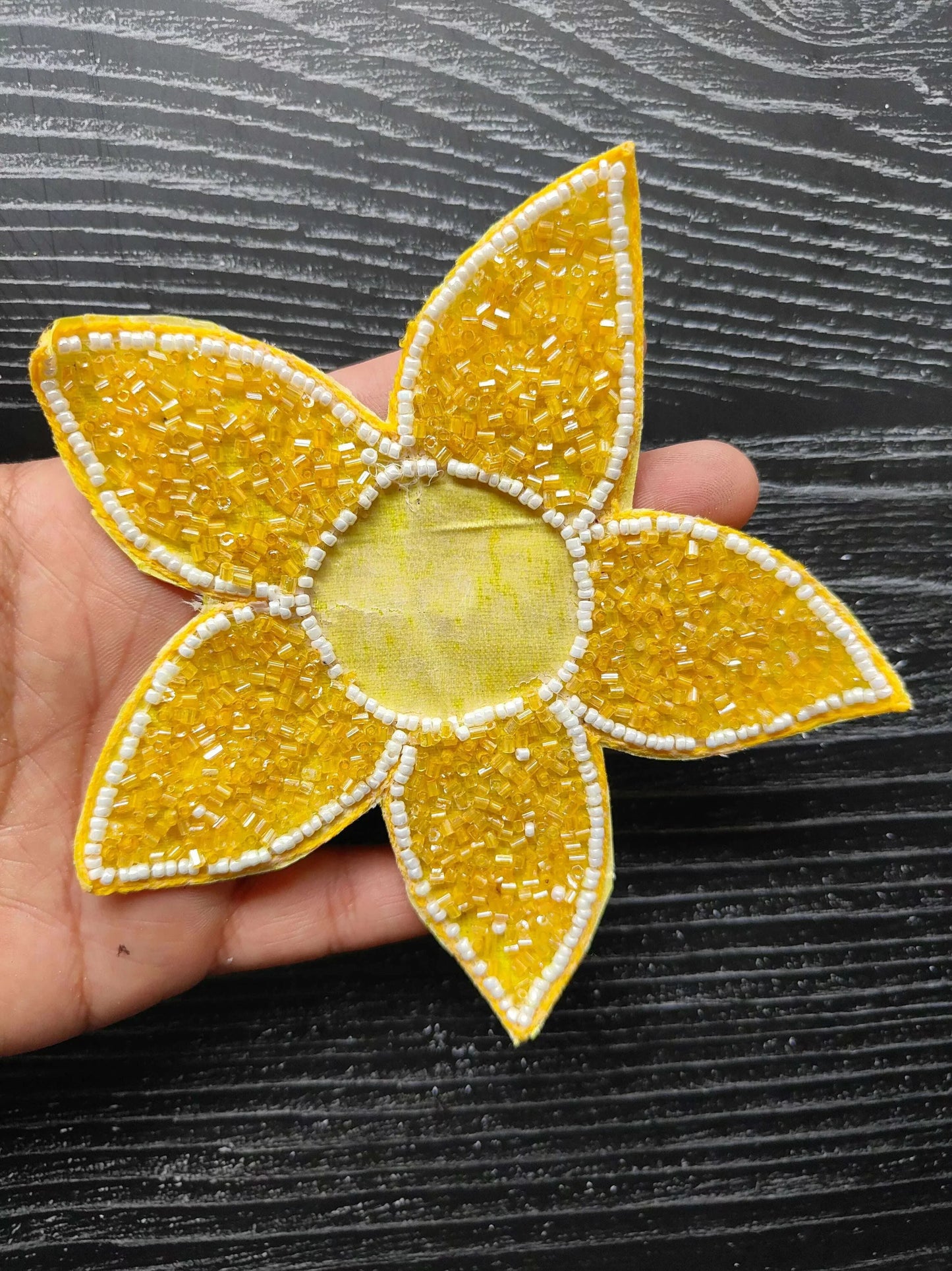 Handheld close-up of yellow beaded star patch with white trim and fabric center