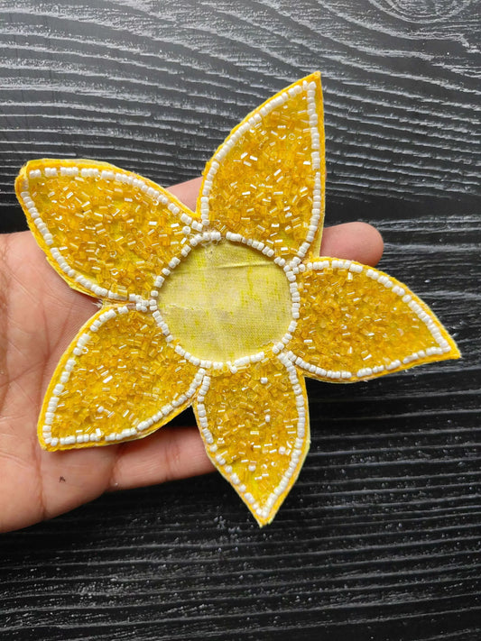 Handheld close-up of yellow beaded star patch with white trim and fabric center