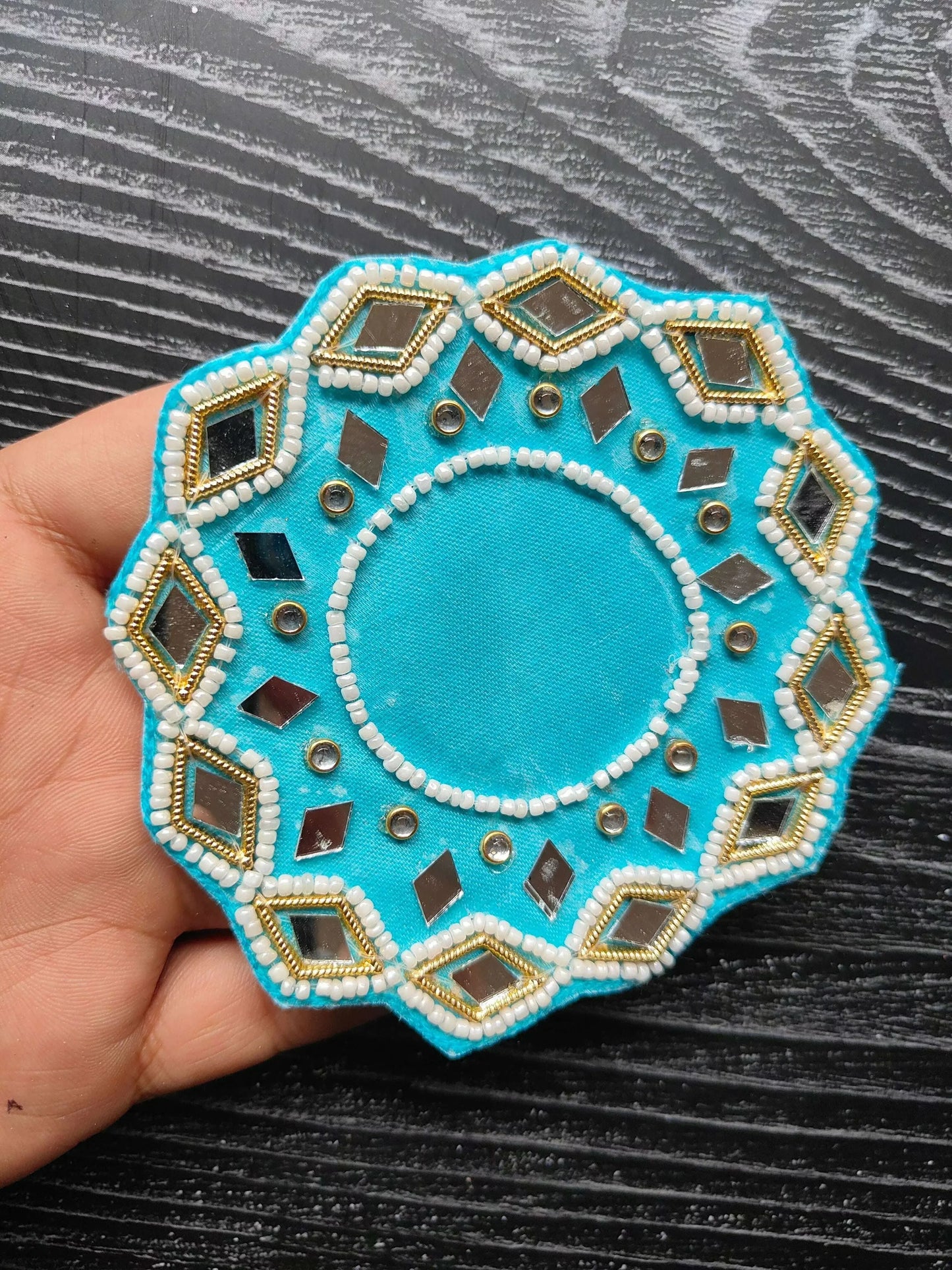 Teal decorative patch with circular center and gold-edged geometric beadwork