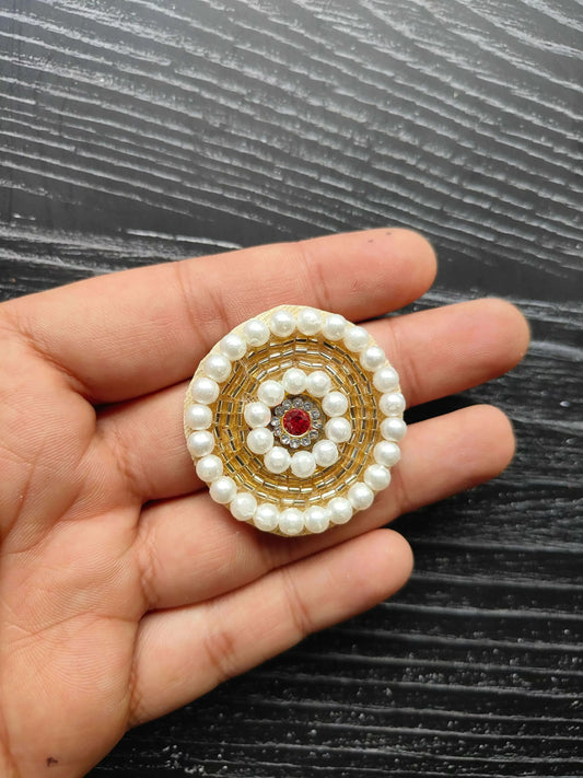 Small round pearl beaded patch with gold border and red center gem, on hand