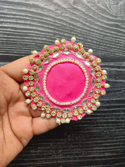 Decorative pink circular patch with pearl border, gold-tone beadwork, and small white bead accents
