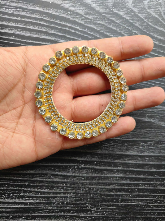 Circular rhinestone patch in hand, gold tone ring with clear stones