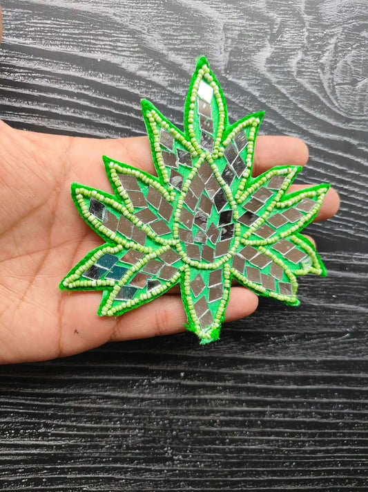 Green star-shaped decorative patch with bead-edged outline and mirrored mosaic center