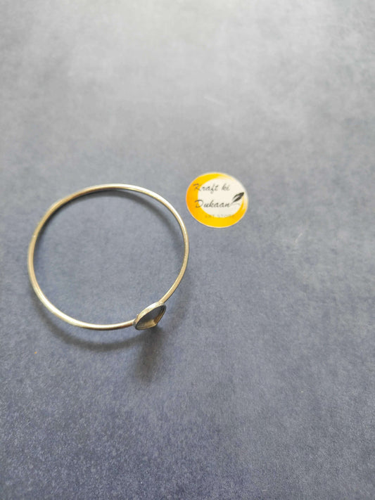 Thin gold-tone bangle bracelet with teardrop end detail, laid flat