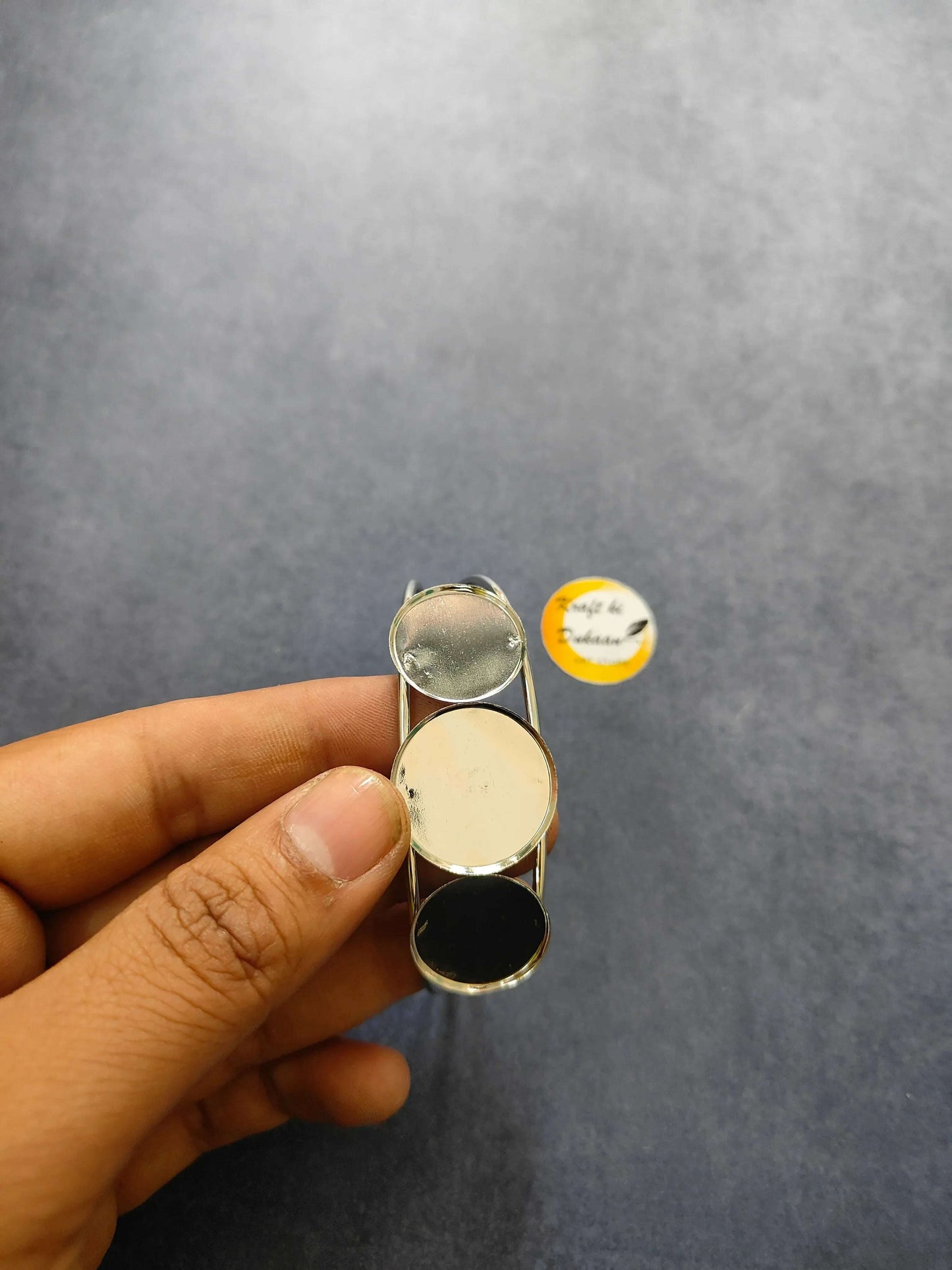 Silver bracelet held in hand; three oval stones with black and light tones