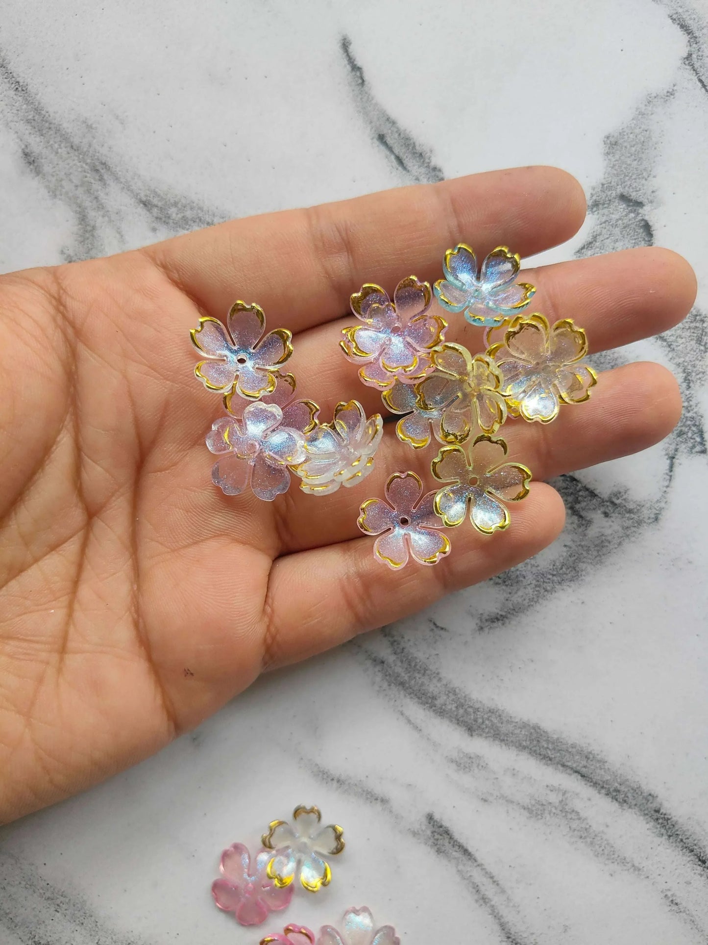 Flower beads in pastel pink, blue, and yellow; shown on an open hand