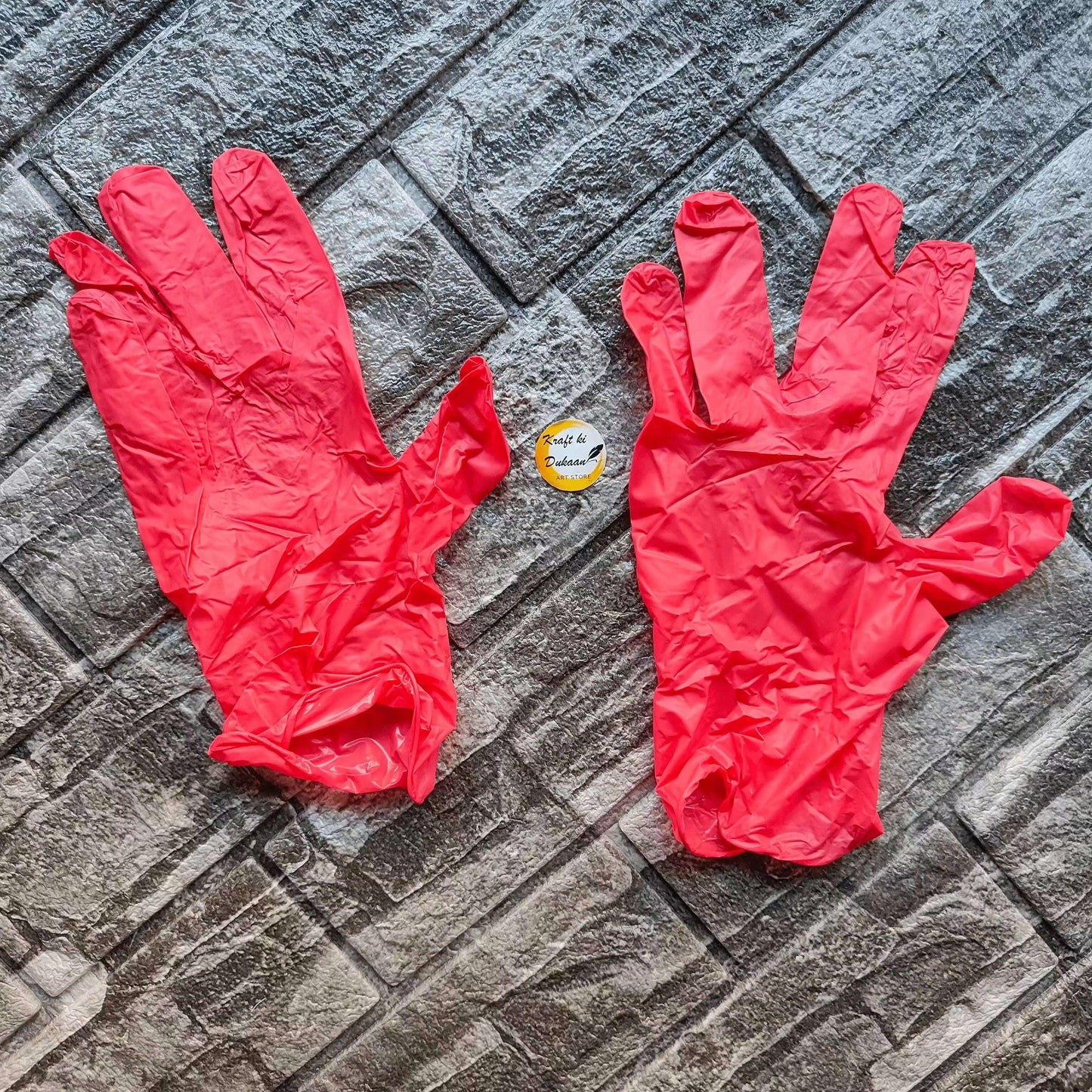 Pair of red vinyl hand gloves, laid flat with finger openings visible