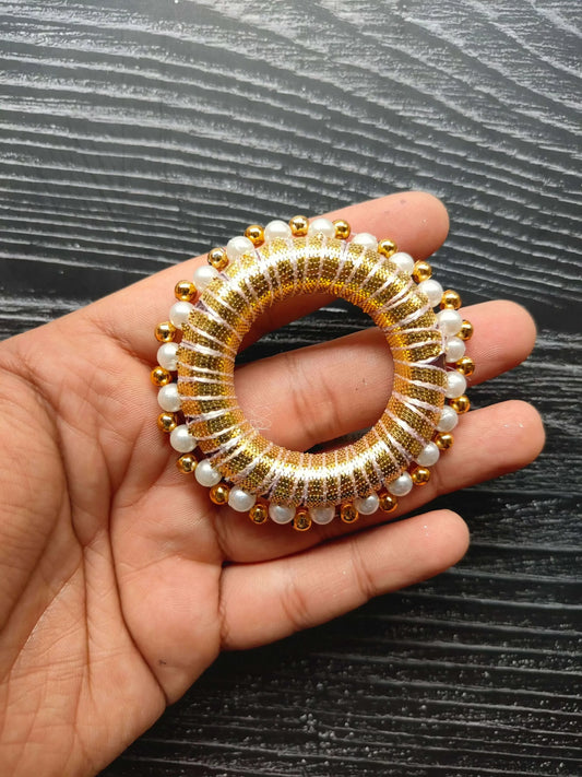 Close-up 2" round golden gota ring with pearl & gold beads, held in hand