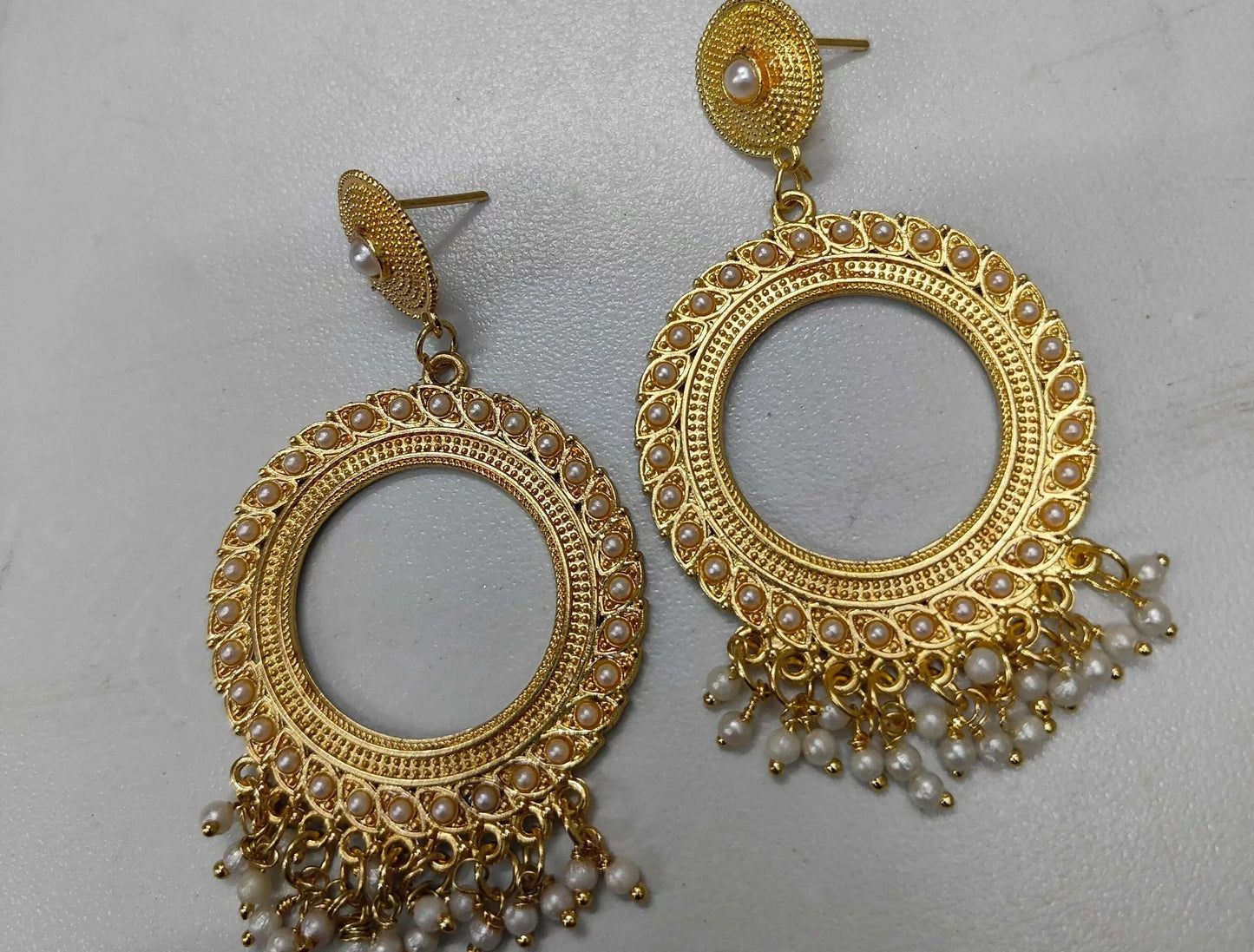 Golden round jhumka earrings with pearl beads and dangling fringe, stud back