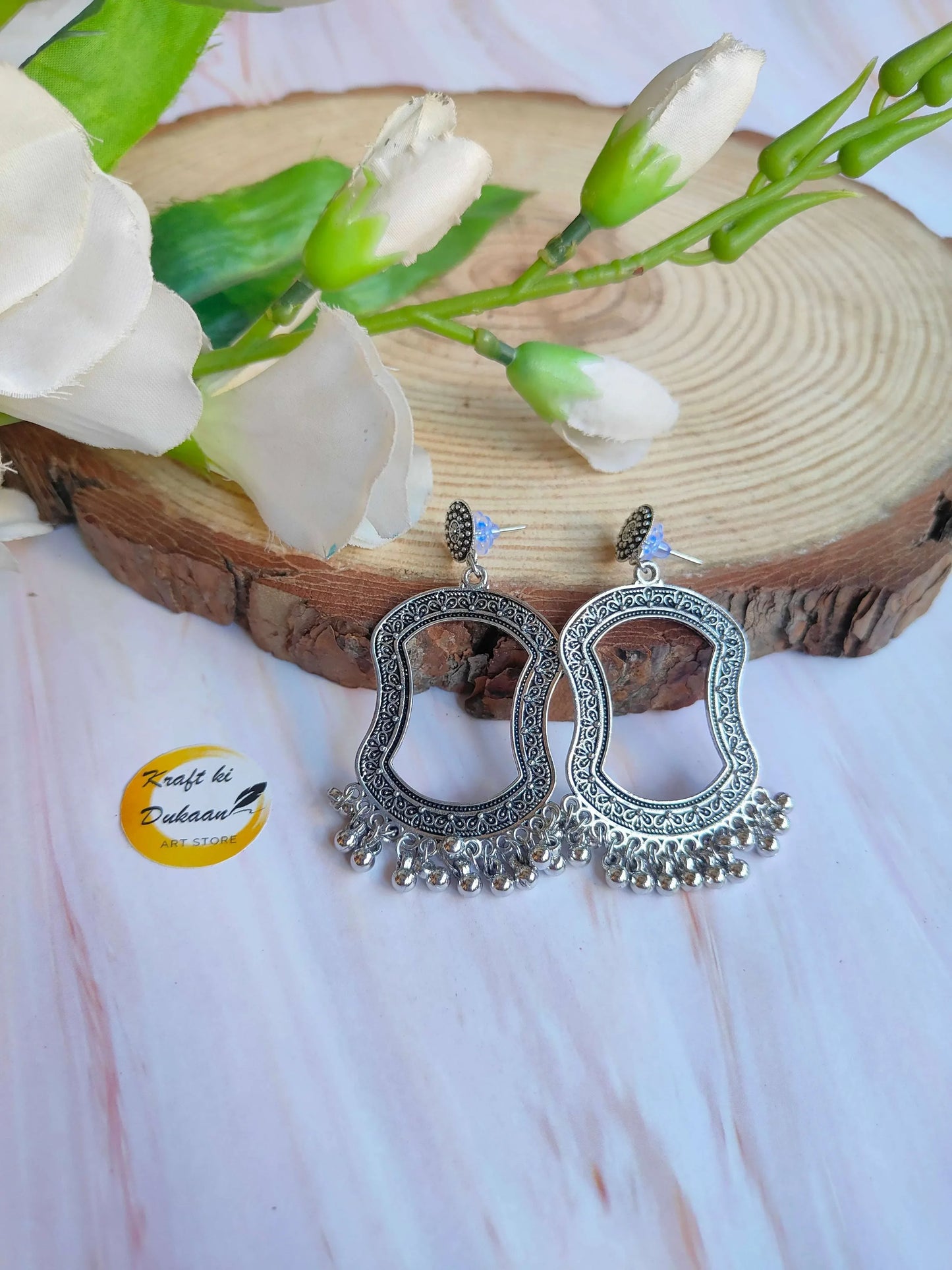 Silver jhumka drop earrings with ornate circular filigree and tiered dangling fringe