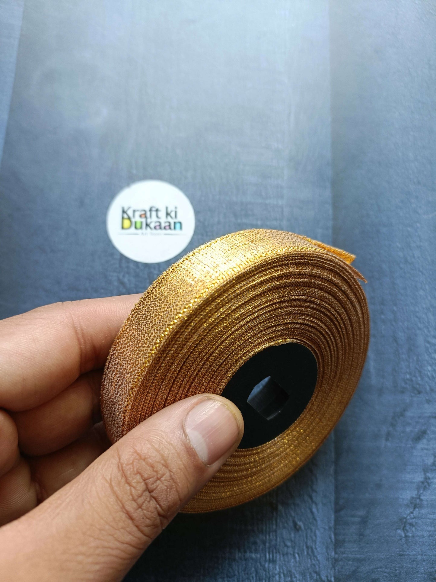 Tissue Ribbon Roll - Golden glitter ribbon roll held in hand