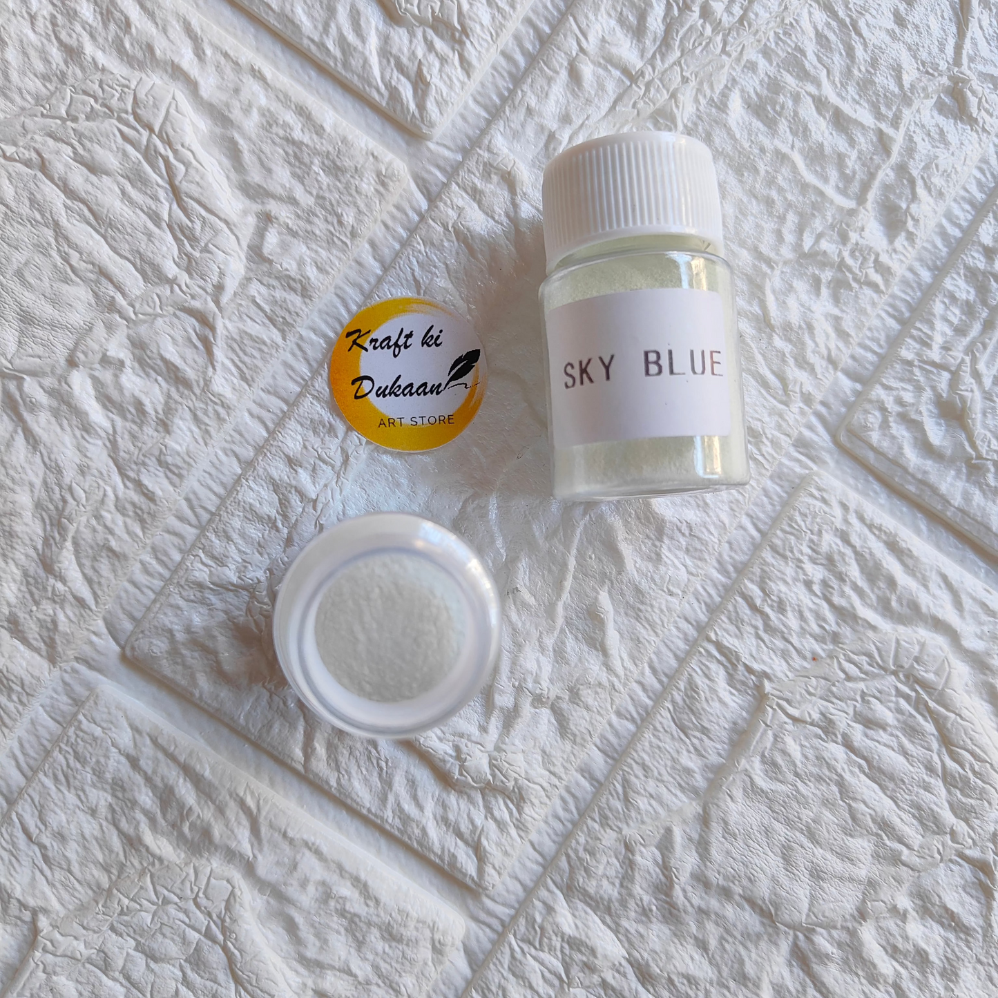 Sky blue glow mica powder for resin in a small container by Kraft ki Dukaan