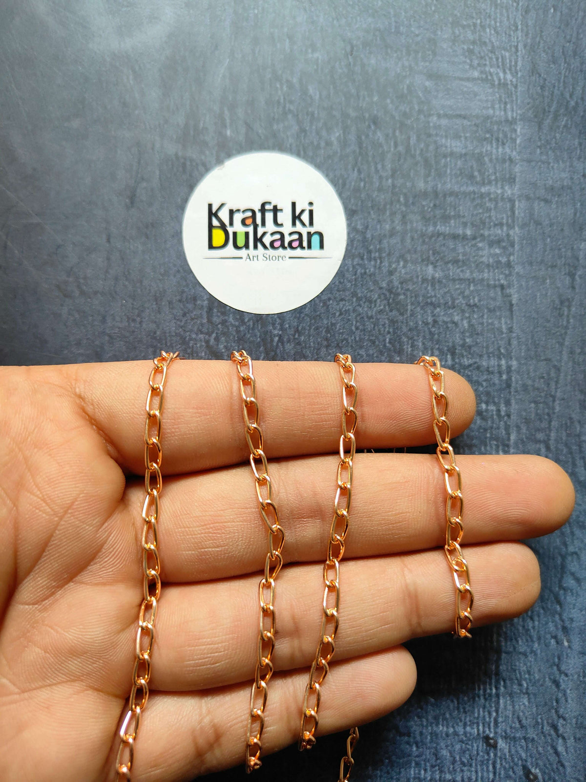 Rose gold tone jewellery chain with chunky rectangular links, hand view