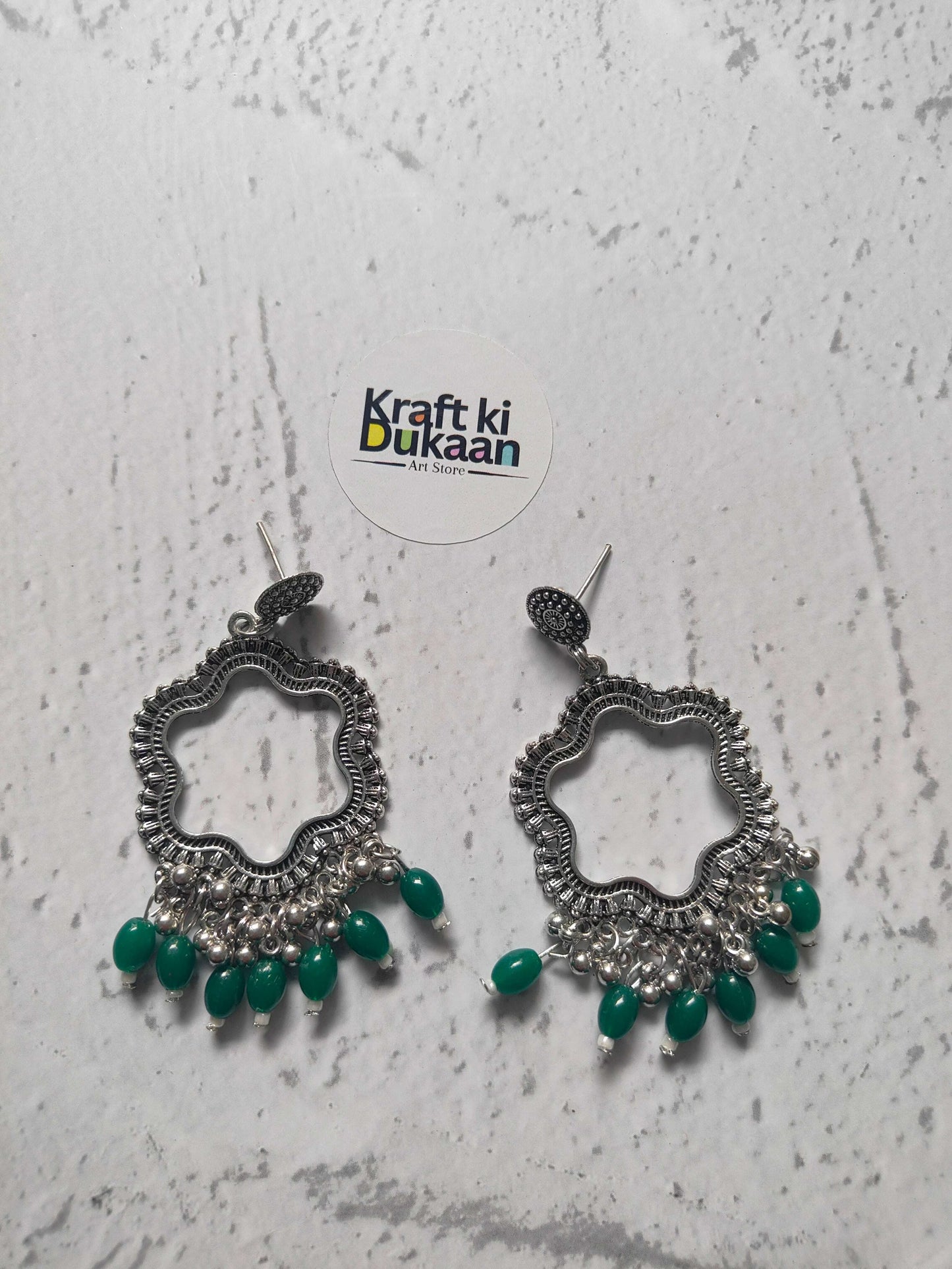 Silver flower jhumka earrings with green bead drops, ornate silver-toned pair