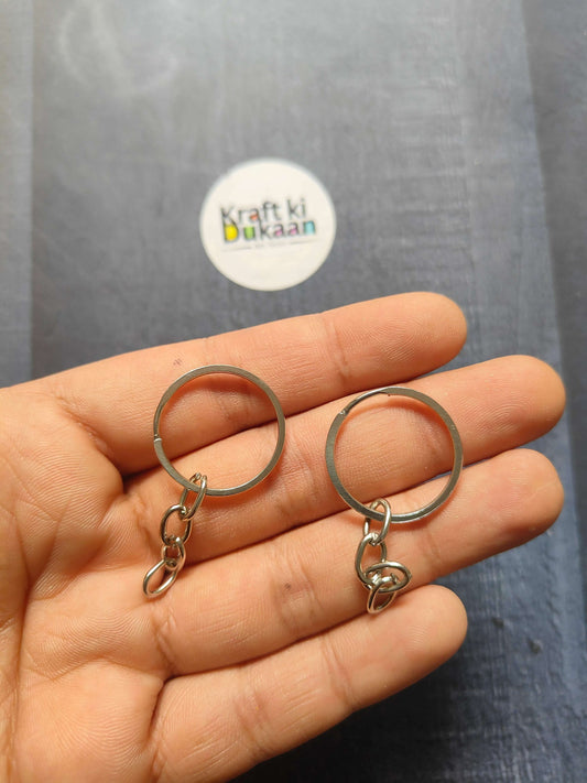 Silver-tone small keychain rings with short chain and clasp, held in hand