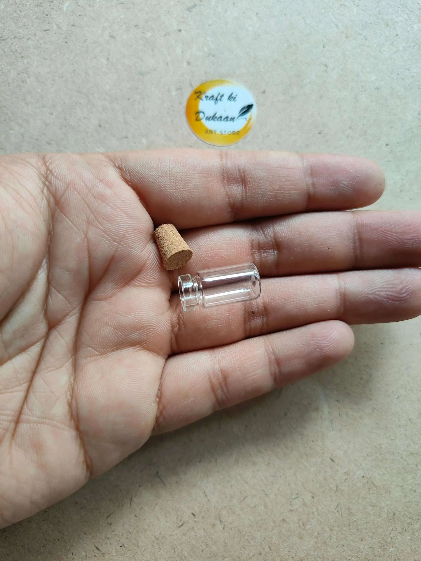 Tiny clear glass vial with cork stopper in an open palm
