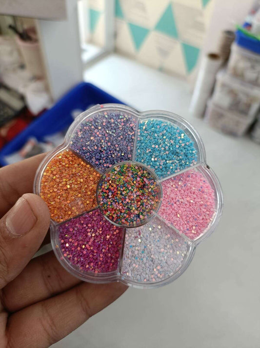 Round glitter box held in hand with multicolor glitter sections and mixed confetti glitter