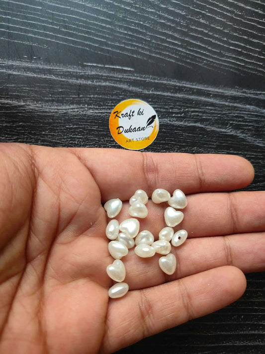 White heart beads in palm, tiny glossy heart pieces