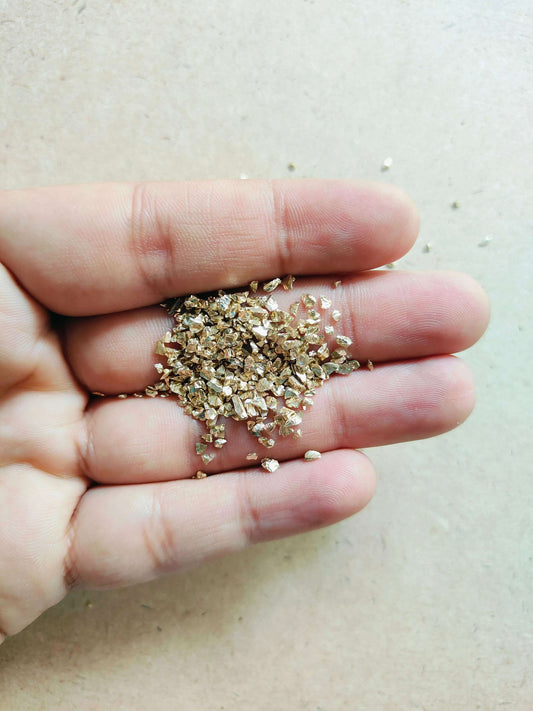 Close-up of light gold granules for resin art held in a hand, perfect for crafting projects