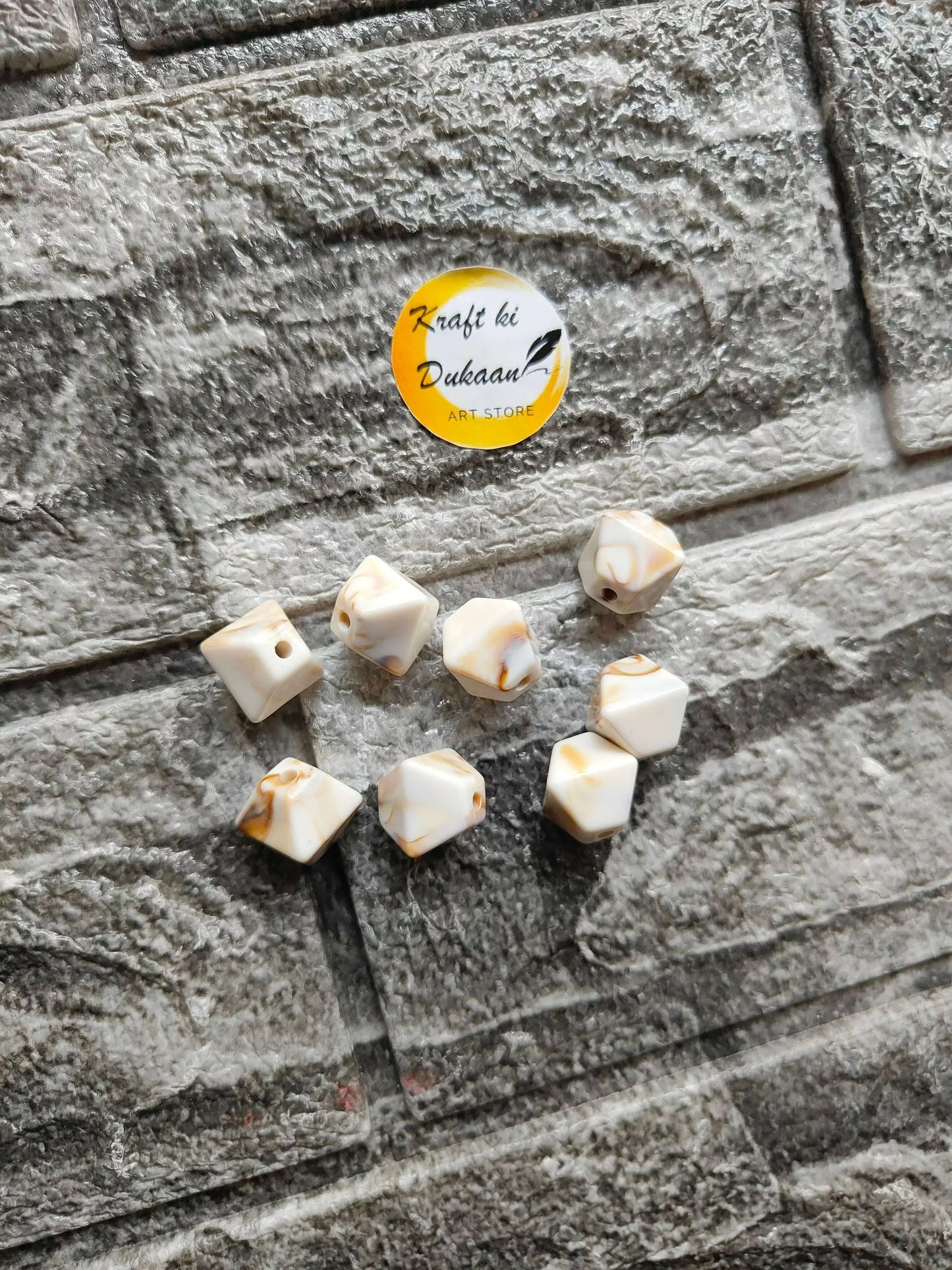 Scattered marble hexagon beads, cream with brown streaks, drilled holes visible