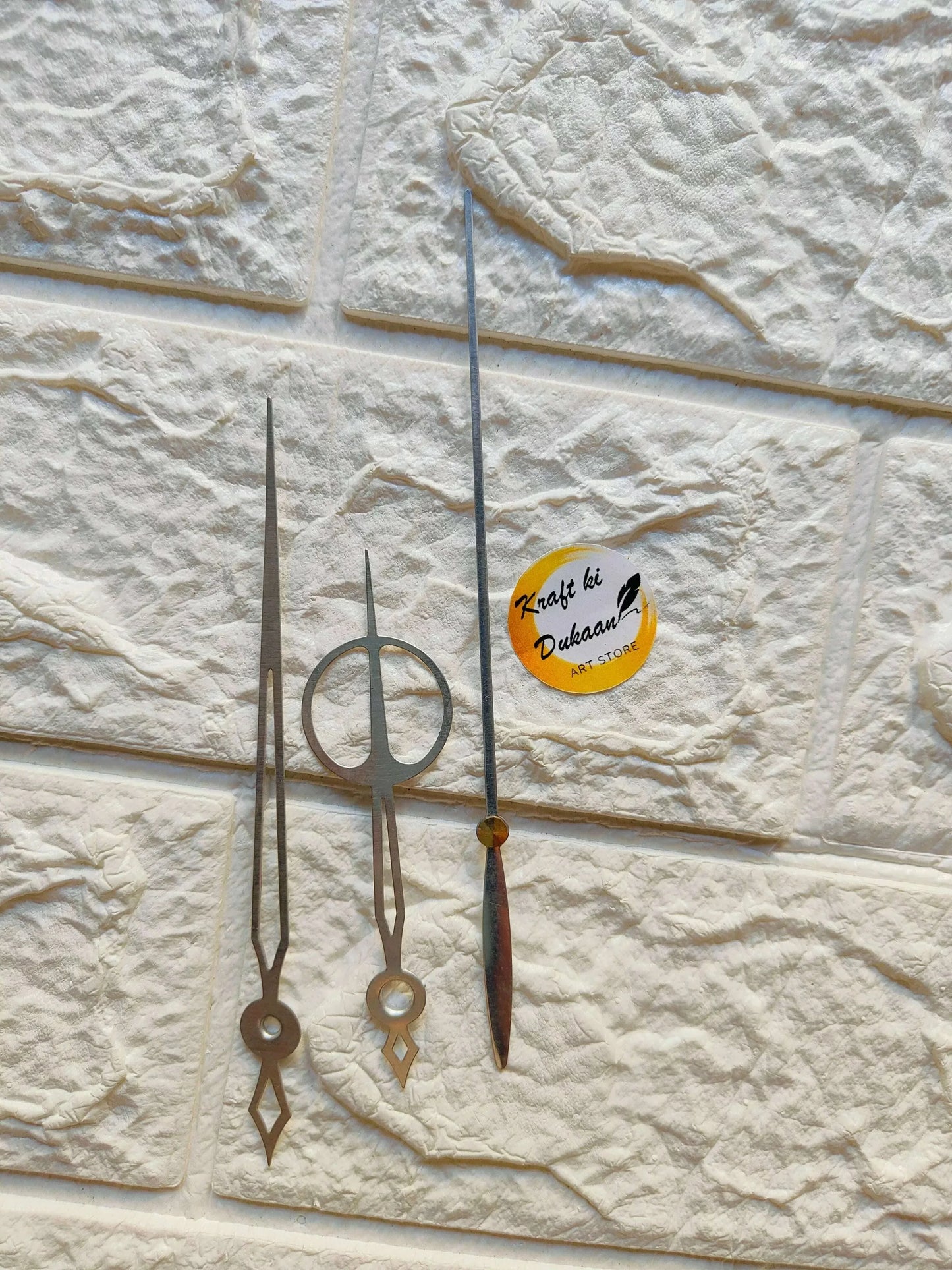 Metal clock hands set in silver finish, with pointed minute and small circular hour hands