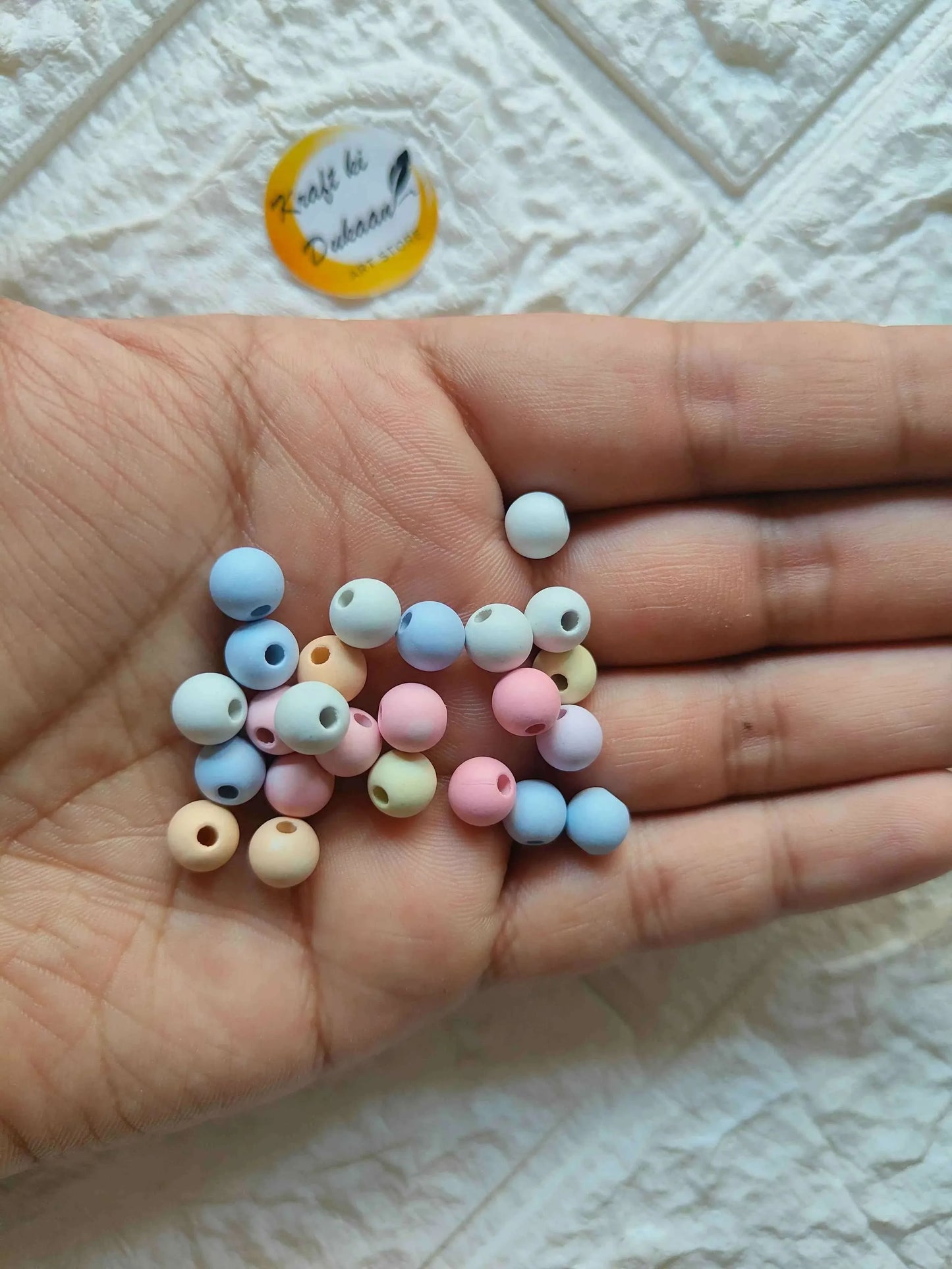 Pastel pearl beads in hand: small round beads in blue, pink, cream, and yellow