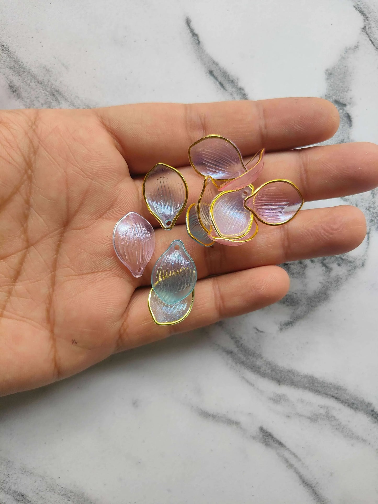 Acrylic petal beads held in hand, iridescent pastel petals with gold-tone edges