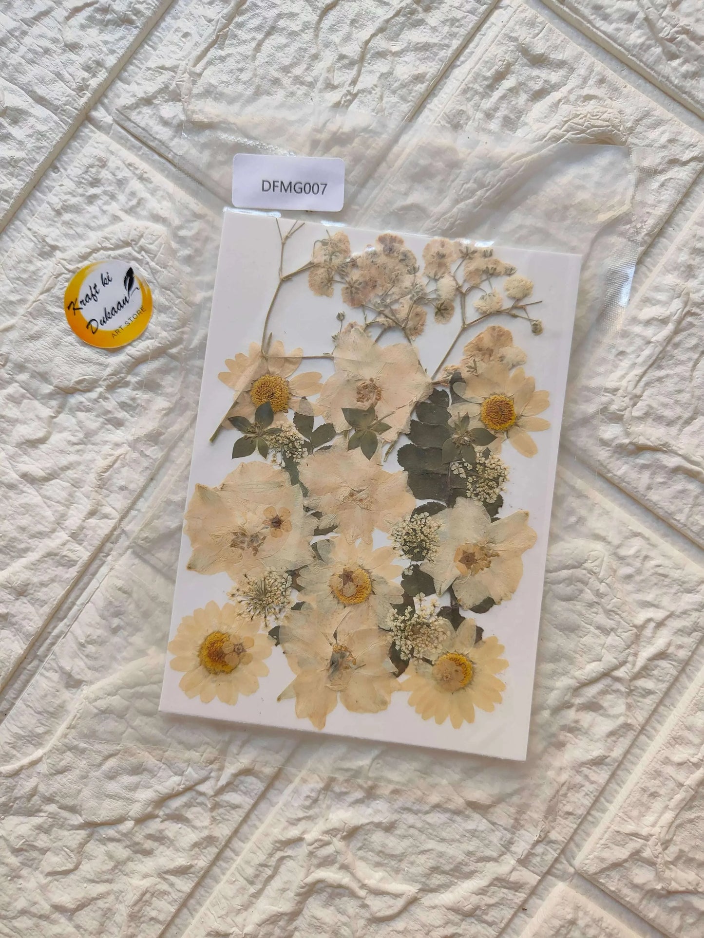Pressed flower sheet with layered beige and yellow blooms on a white backing
