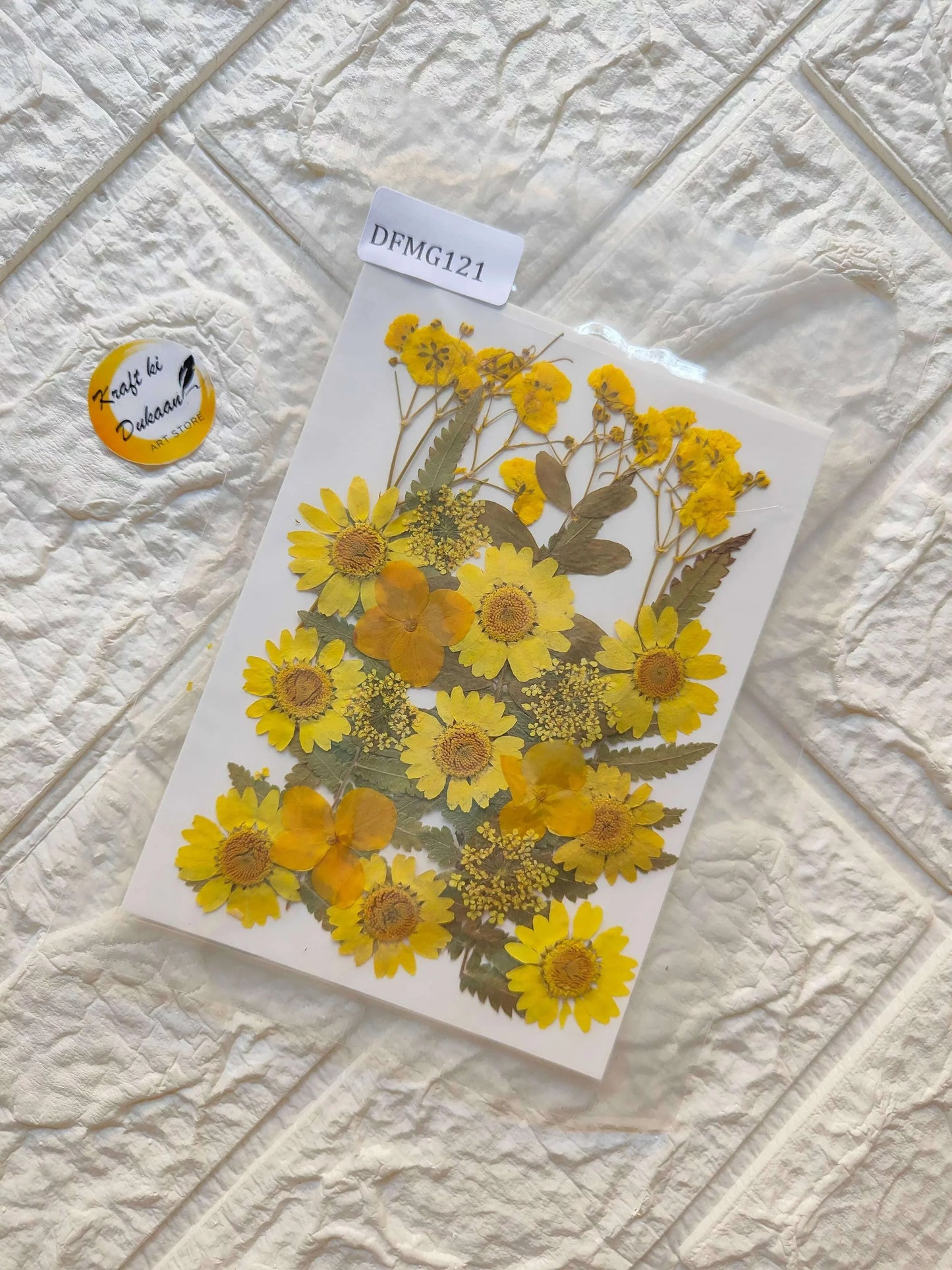Pressed flower sheet with yellow blooms and small leaves in a clear plastic pack