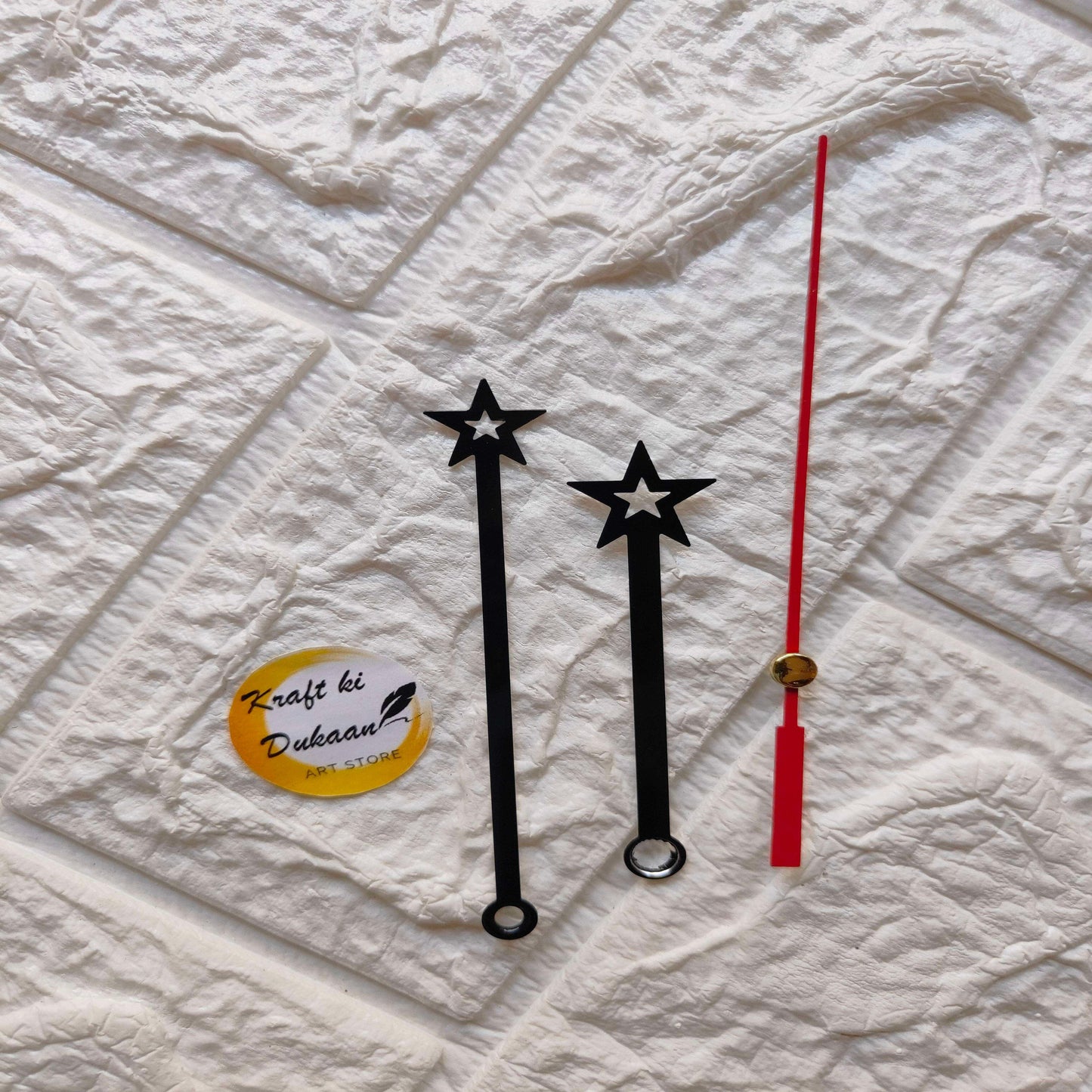 Red and black metal clock hands set with star tips and pendulum-style weight
