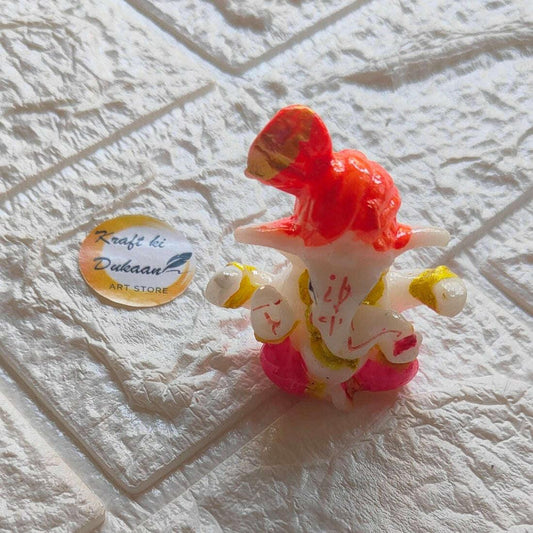 Ganpati idol from side view, red head and trunk, white face, pink and gold ornaments