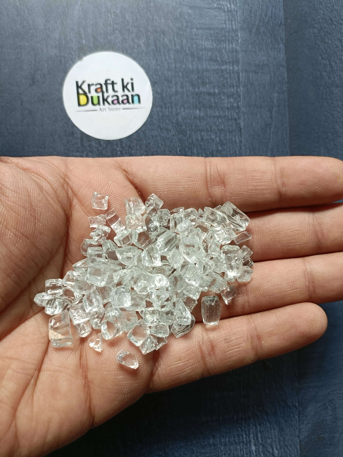 Transparent crystal stones, small clear faceted chunks scattered in palm.