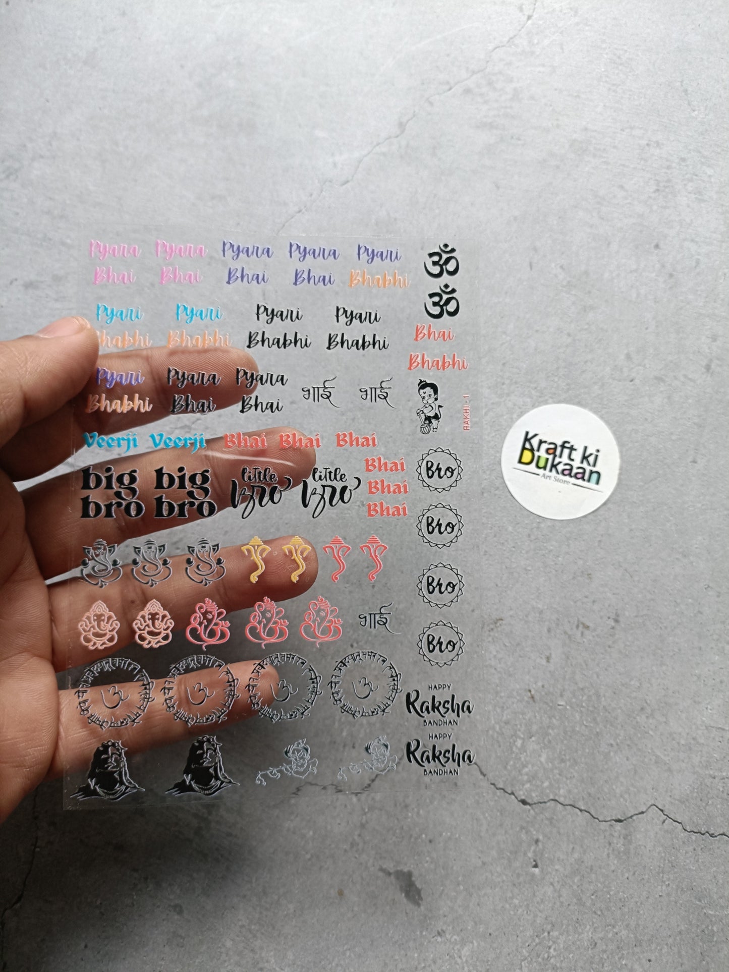 UV DTF peel-off sticker sheet close-up with colored 'Bhai' text and decorative icons