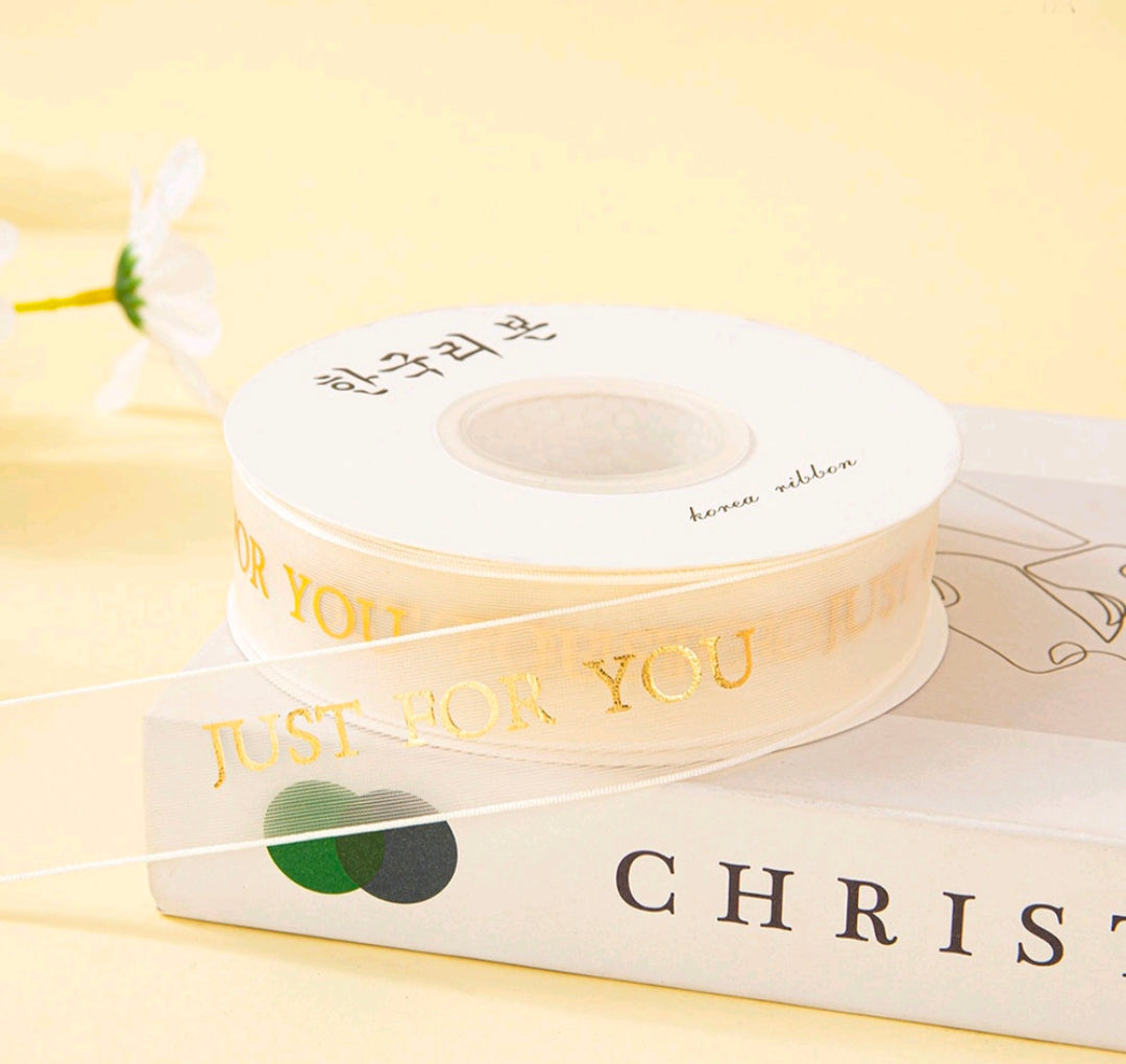 Off-white printed ribbon roll with repeating text and a small heart graphic