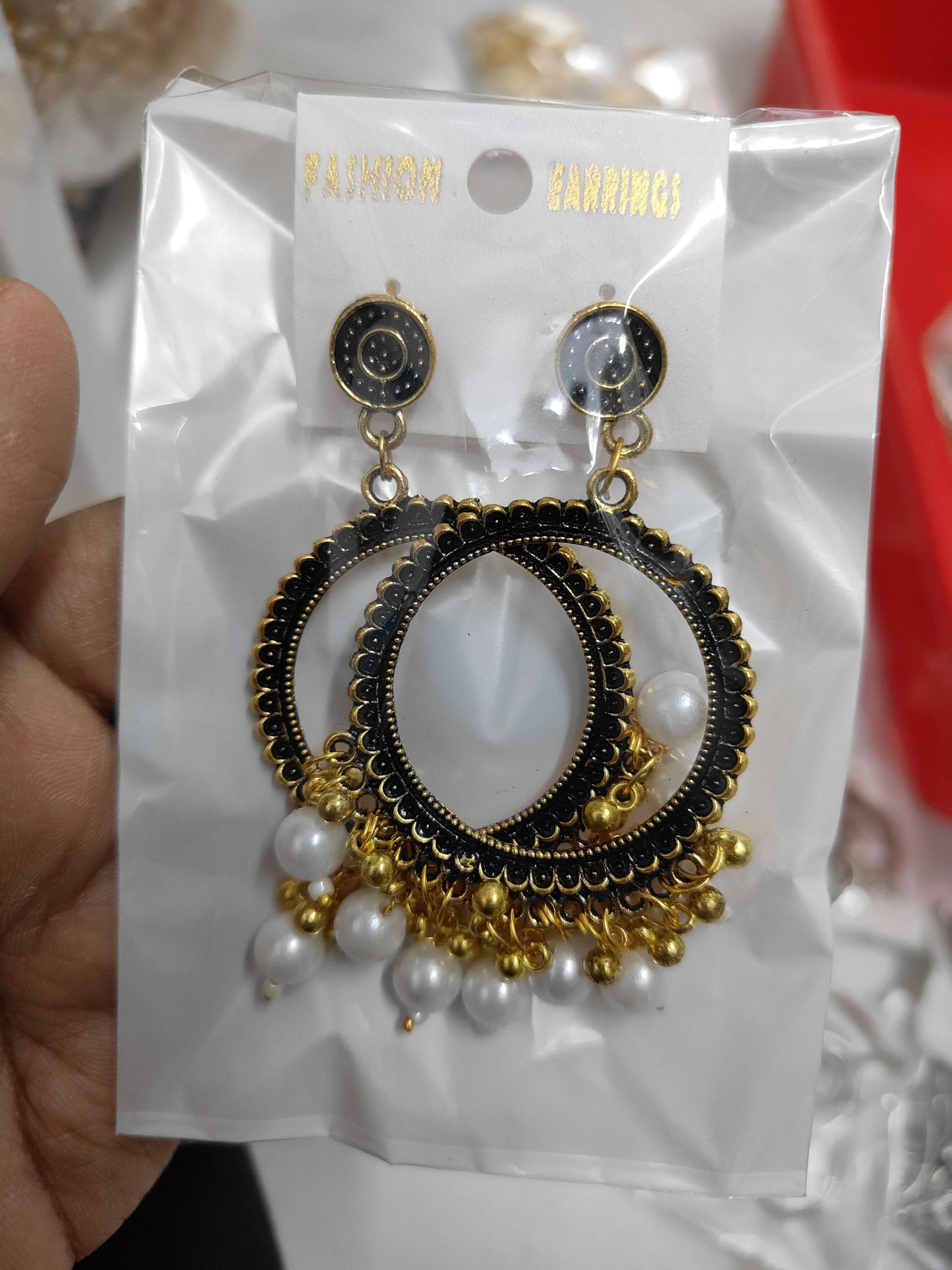 Golden round jhumka earrings with black detailing and white bead tassels